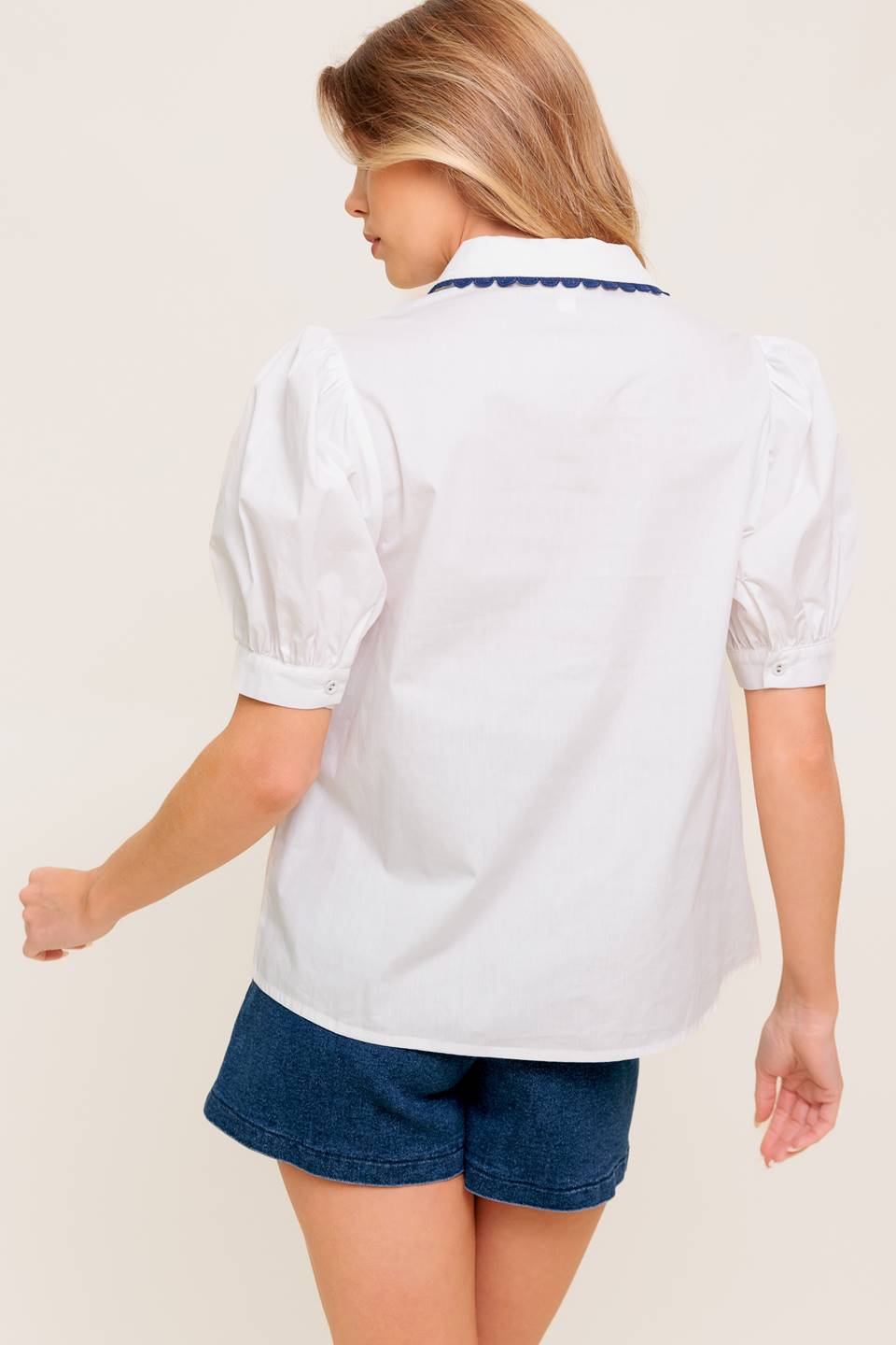 A solid woven top featuring collar, button down, short puff sleeve and laced edge.