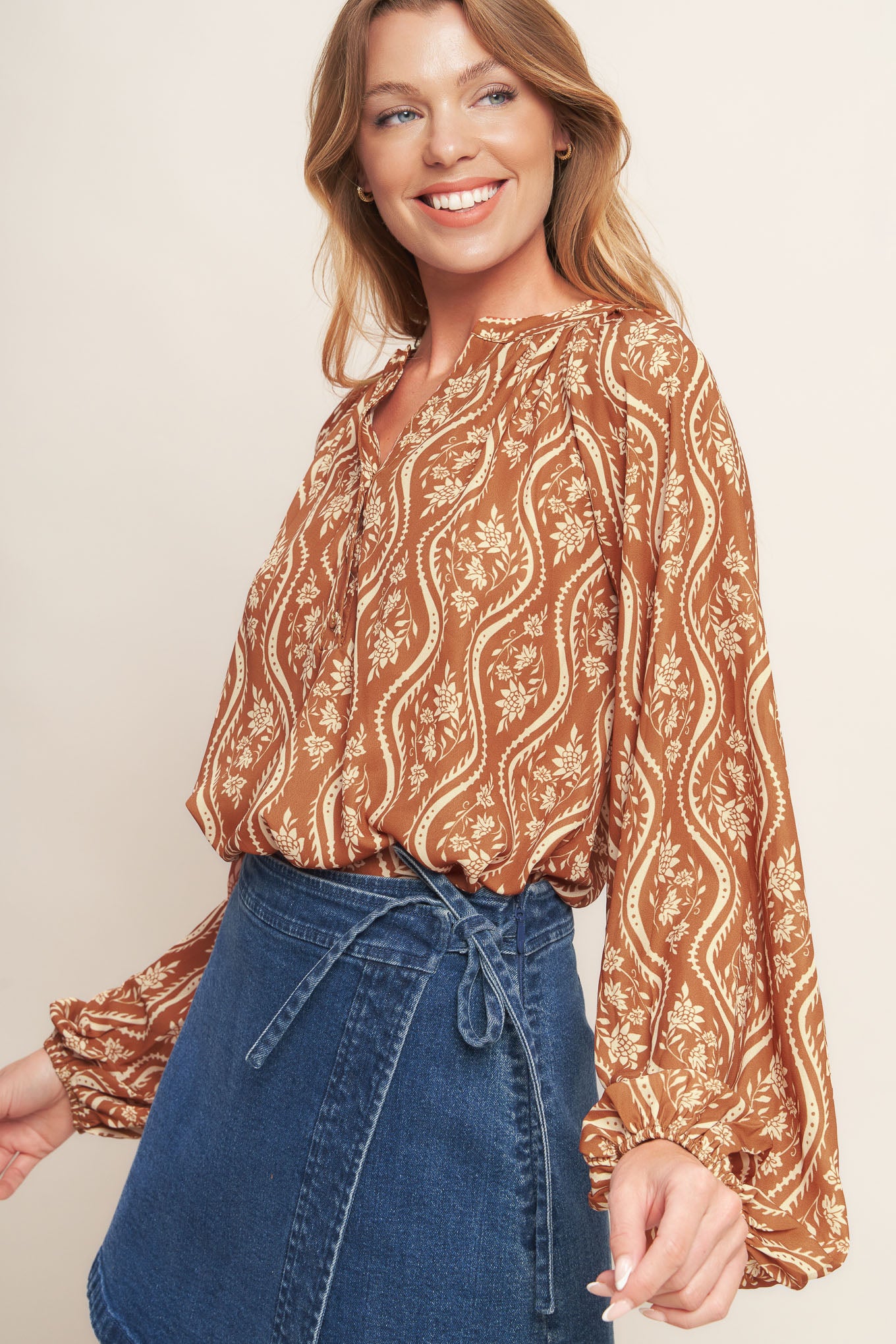 A printed woven top featuring round neckline with V front and long raglan sleeve