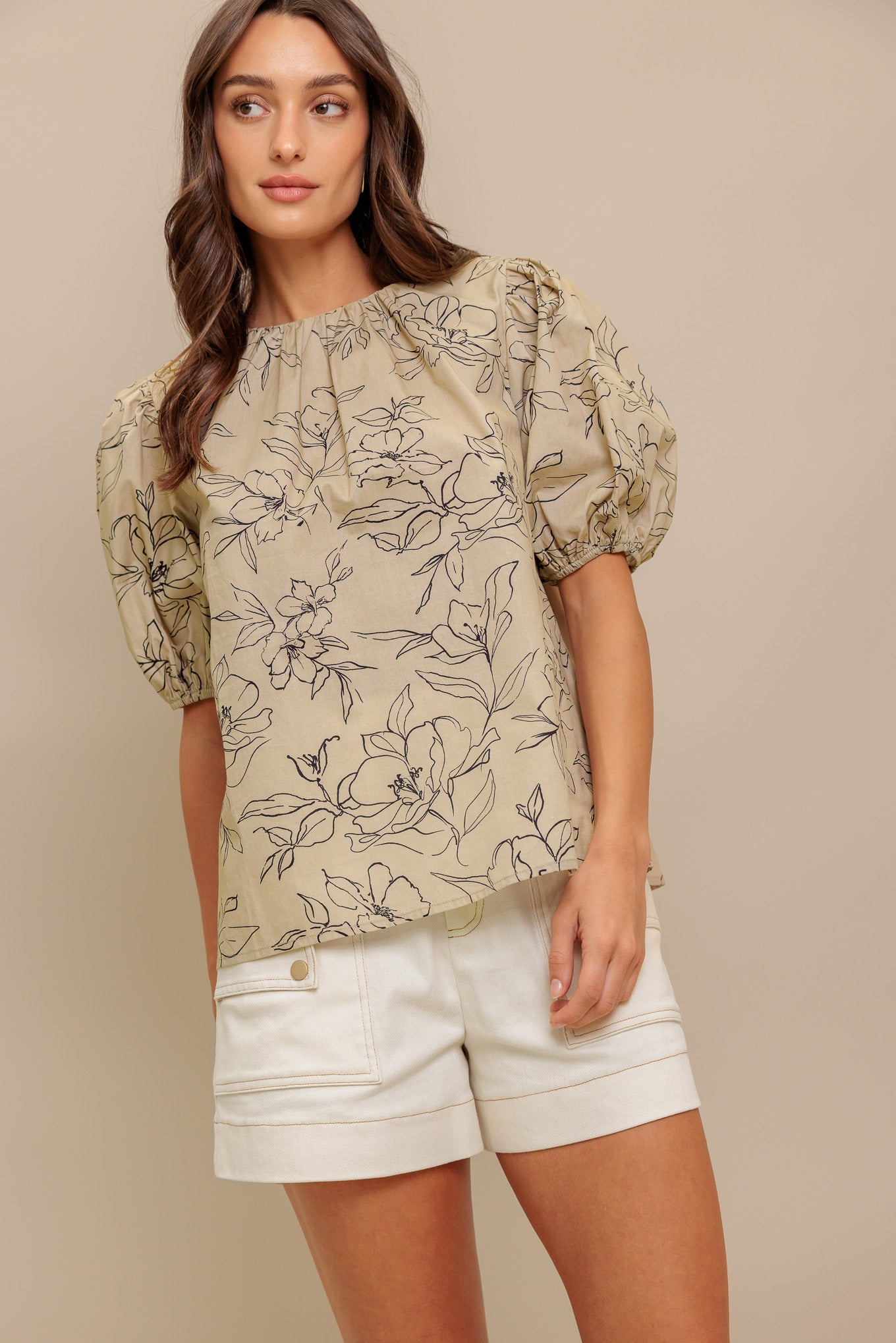 A printed woven top featuring round neckline, short puff sleeve and back neck tie closure