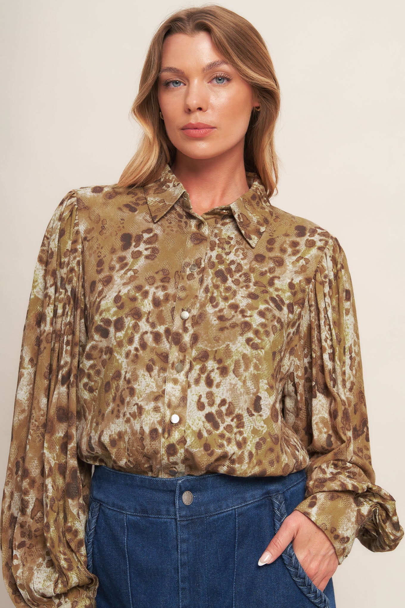 A printed woven top featuring collar, front button down and long blouson sleeve with cuff