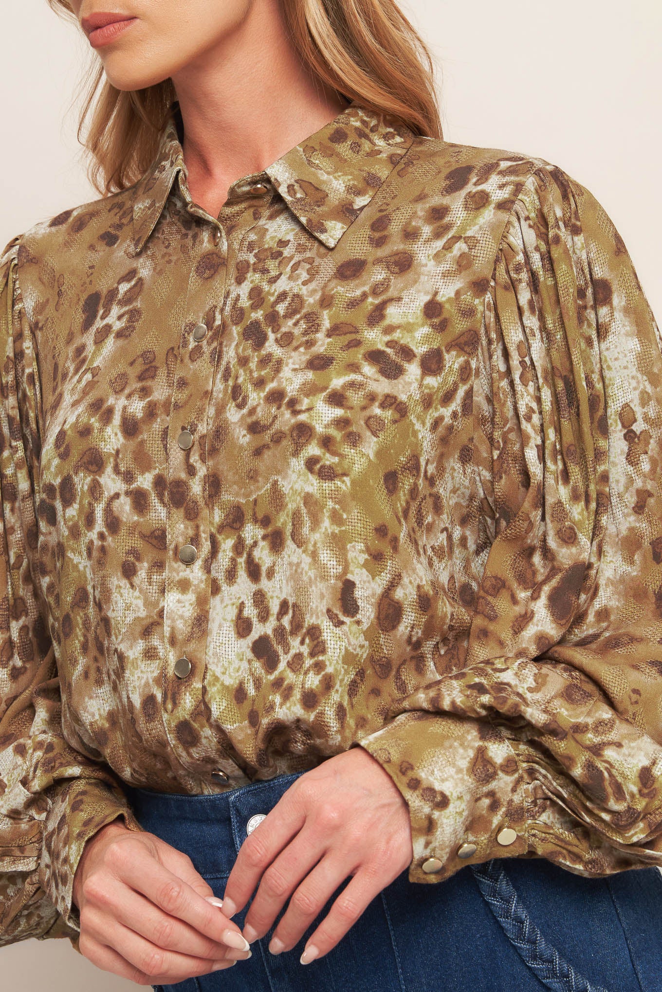 A printed woven top featuring collar, front button down and long blouson sleeve with cuff