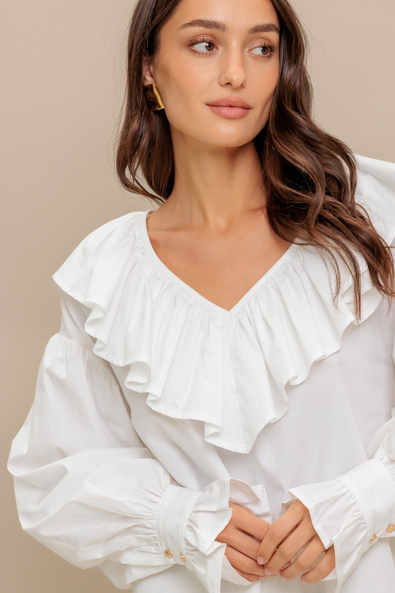 A solid woven top featuring V neckline with ruffles and long puff sleeve with cuff