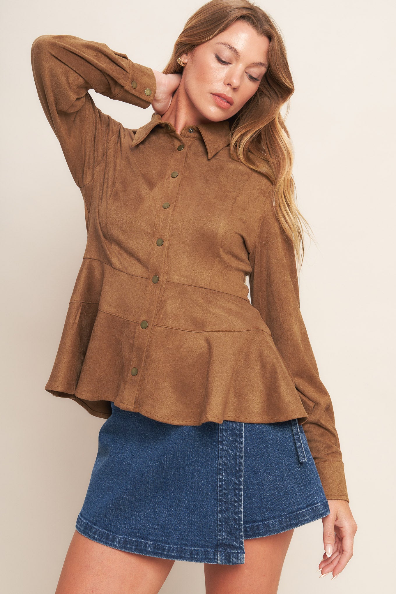 A faux suede top featuring collar, long sleeve, front button down and peplum.