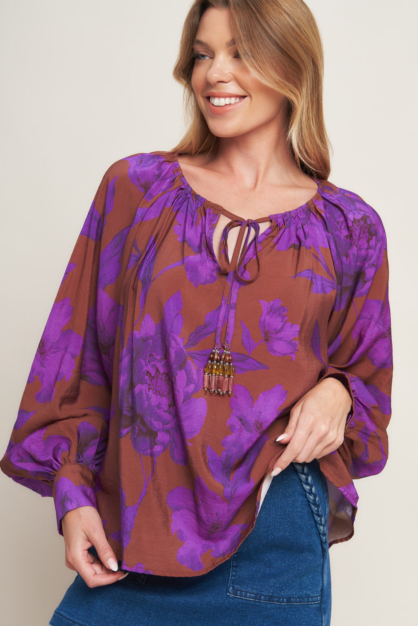 A printed woven peasant top featuring round neckline with tie and long sleeve with cuff