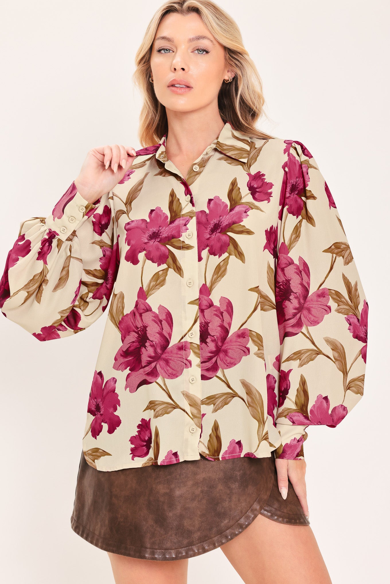 A woman modeling a cream-colored long-sleeve button-up blouse with a bold magenta and brown floral print | Flying Tomato