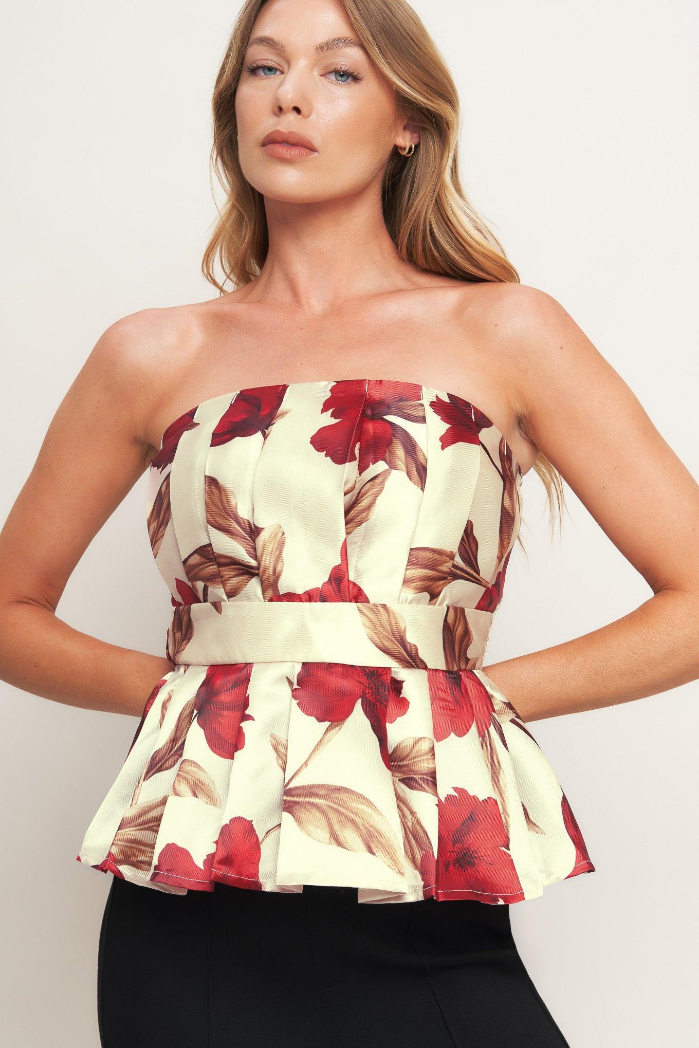 A printed woven top featuring strapless neckline, pleated body, peplum and smocked back bodice.
