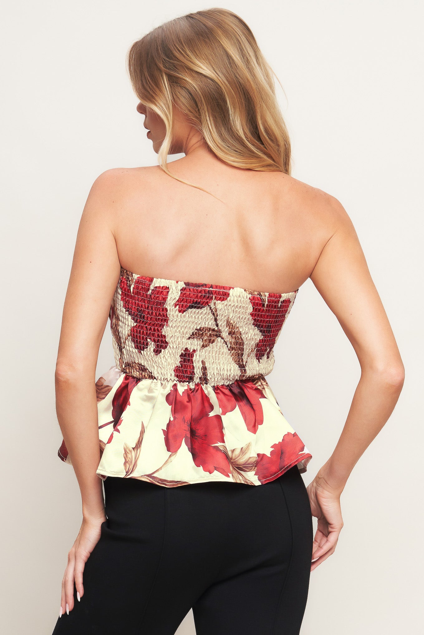 A printed woven top featuring strapless neckline, pleated body, peplum and smocked back bodice.