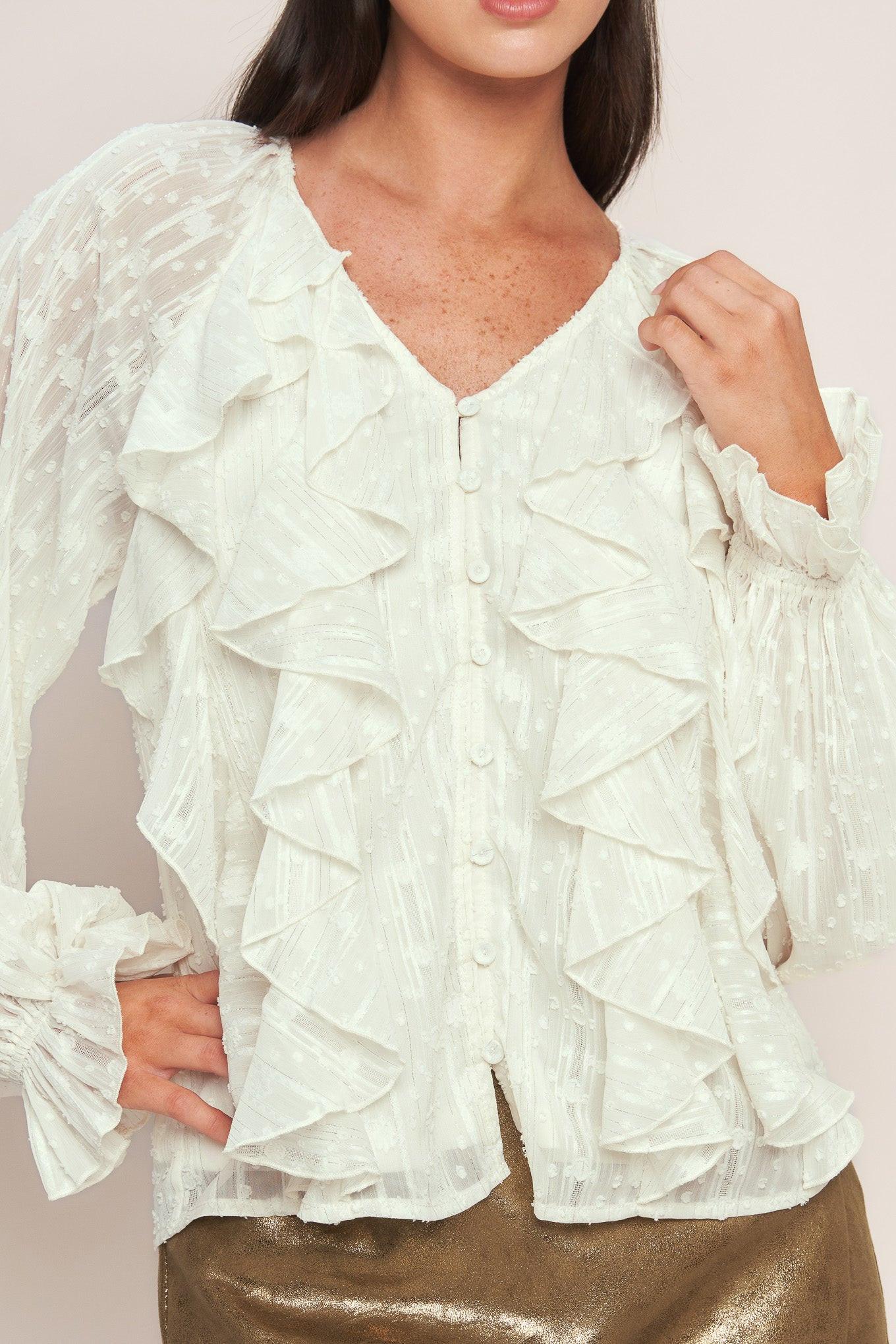 A textured woven top featuring V neckline, front button down, ruffled bodice and long blouson sleeve with ruffled cuff