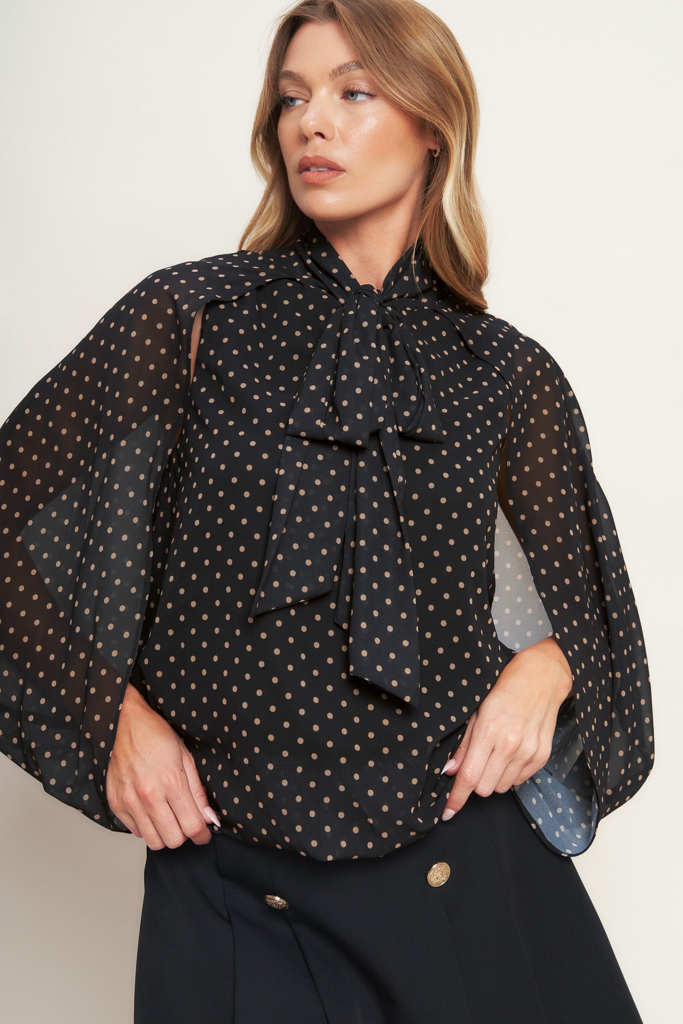 A woven dotted top featuring front bow tie and capelet.