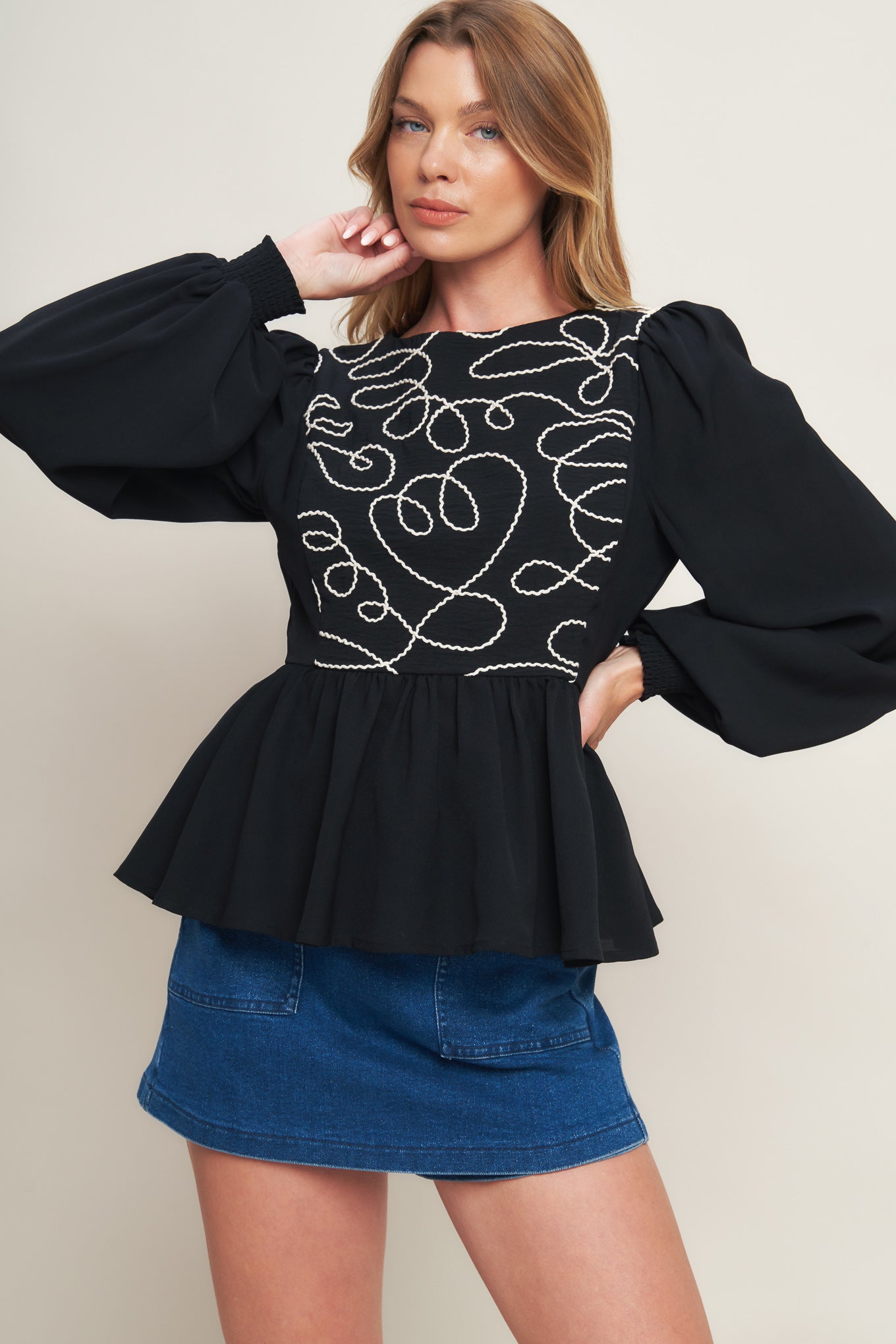 A solid woven top featuring round neckline, long sleeve, embellished bodice, peplum and back zipper closure