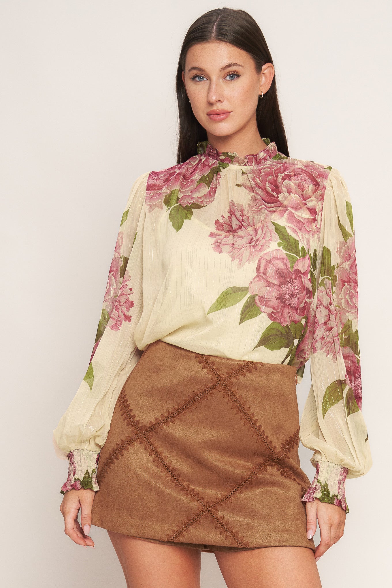 A printed woven top featuring ruffled high neckline, long sleeve with smocked cuff, back neck button closure and cami