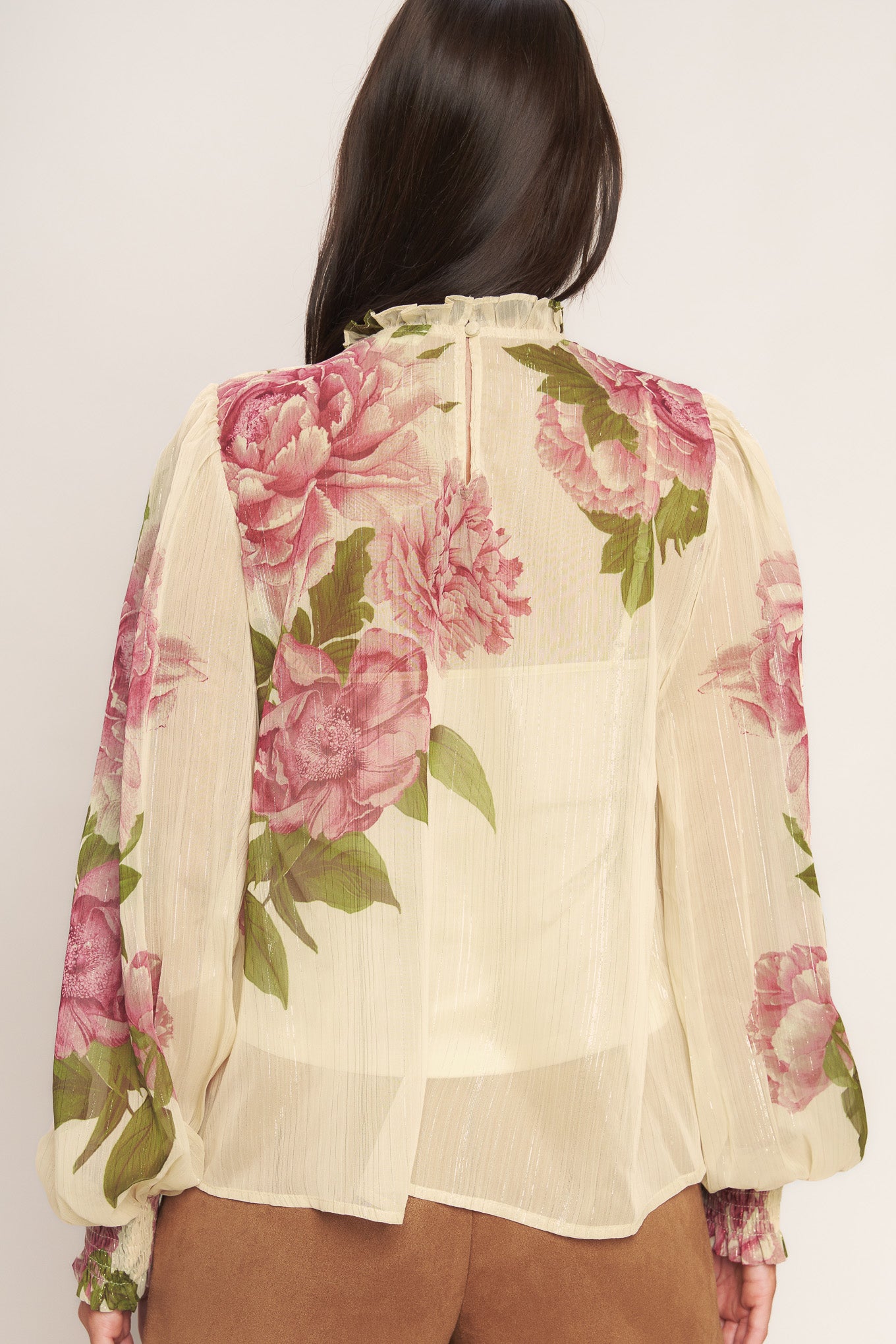 A printed woven top featuring ruffled high neckline, long sleeve with smocked cuff, back neck button closure and cami