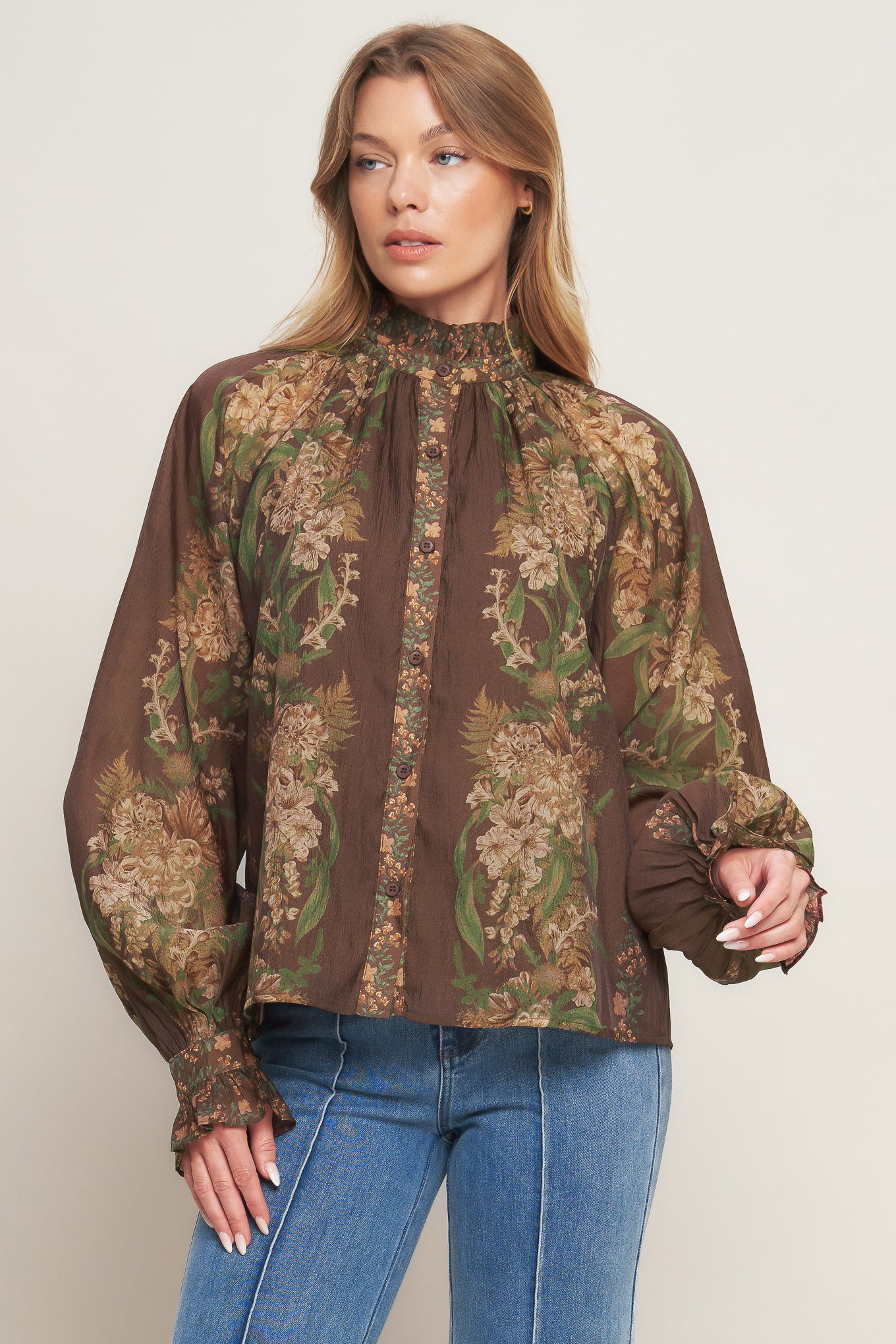 A printed woven top featuring ruffled high neckline, long sleeve with cuff and front button down closure