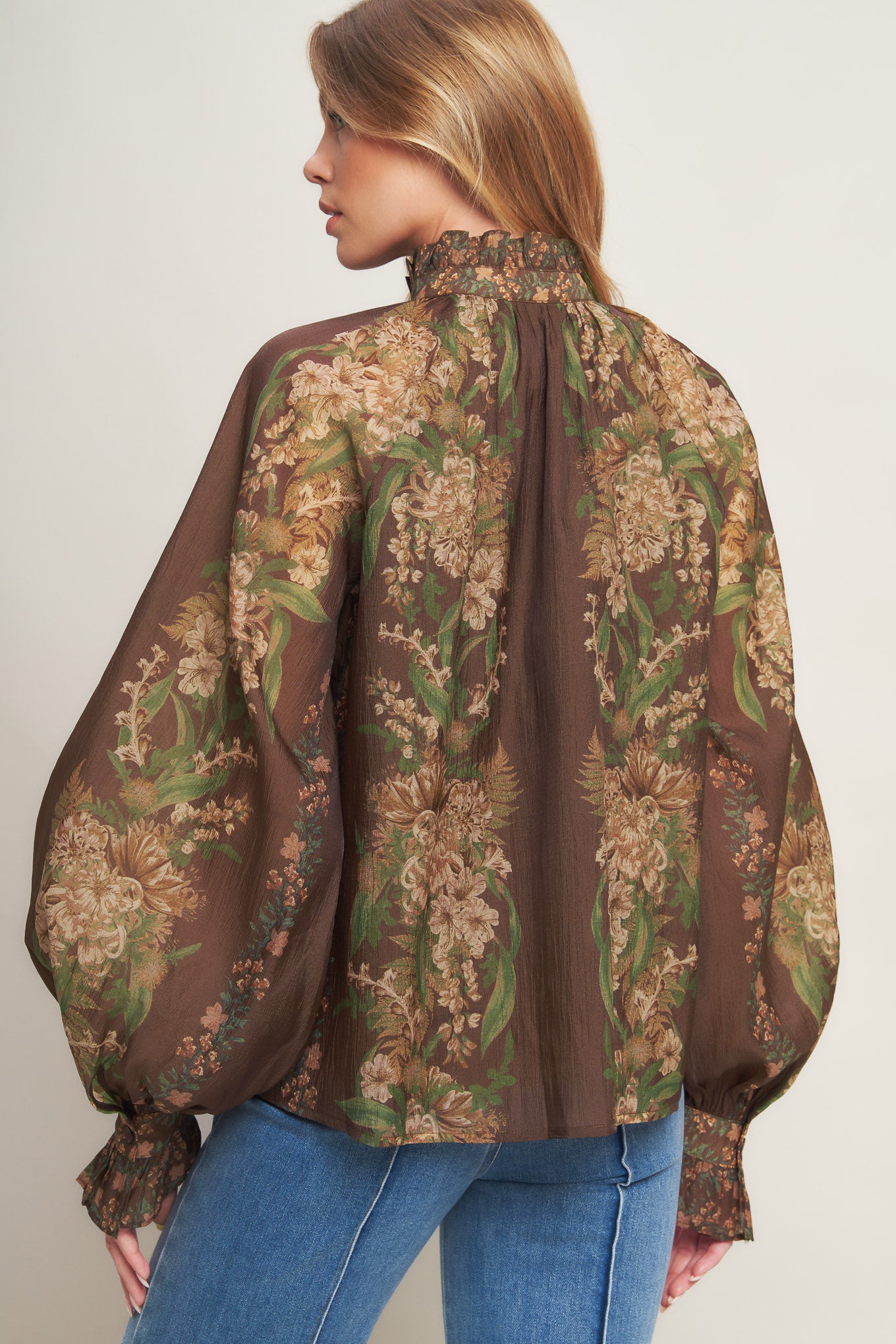 A printed woven top featuring ruffled high neckline, long sleeve with cuff and front button down closure