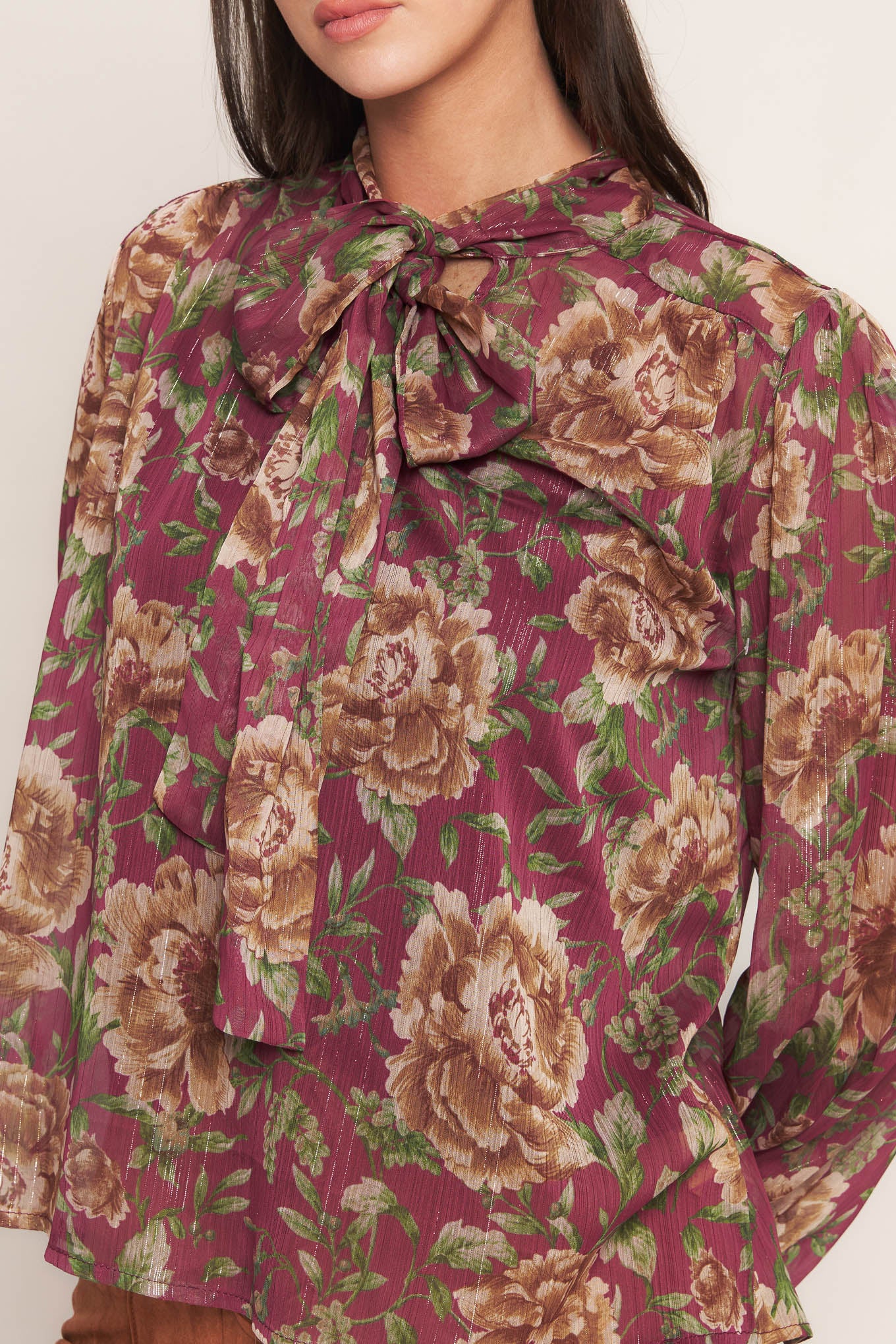 A printed woven top featuring front bow tie and long sleeve with smocked cuff