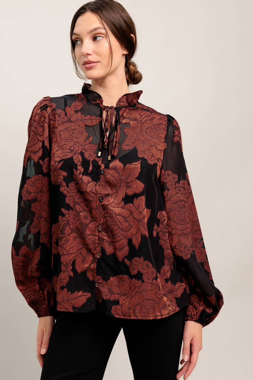Woman wearing a black and red floral blouse against a plain background