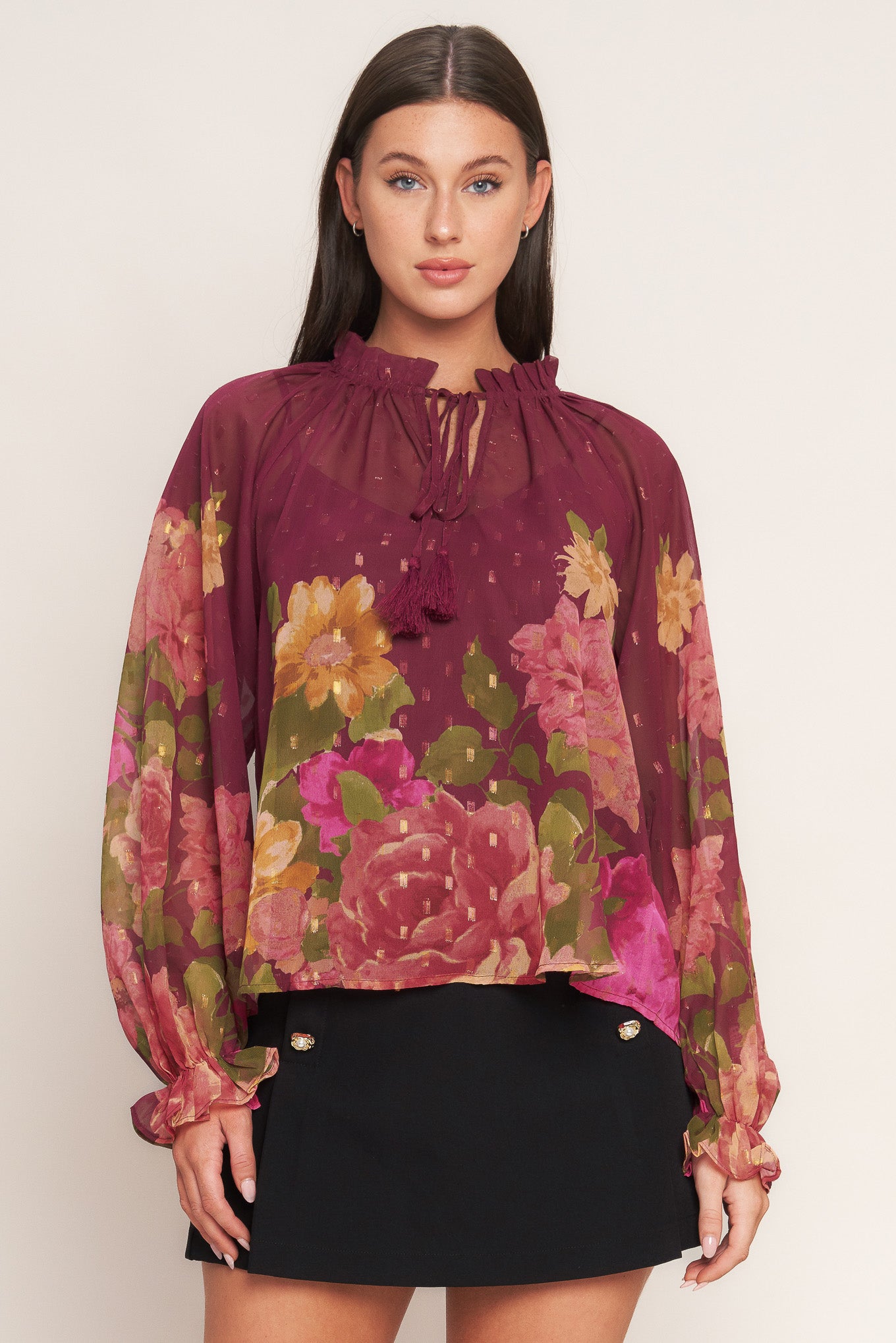 A printed textured woven top featuring ruffled round neckline with front tie, long sleeve with ruffled cuff and cami