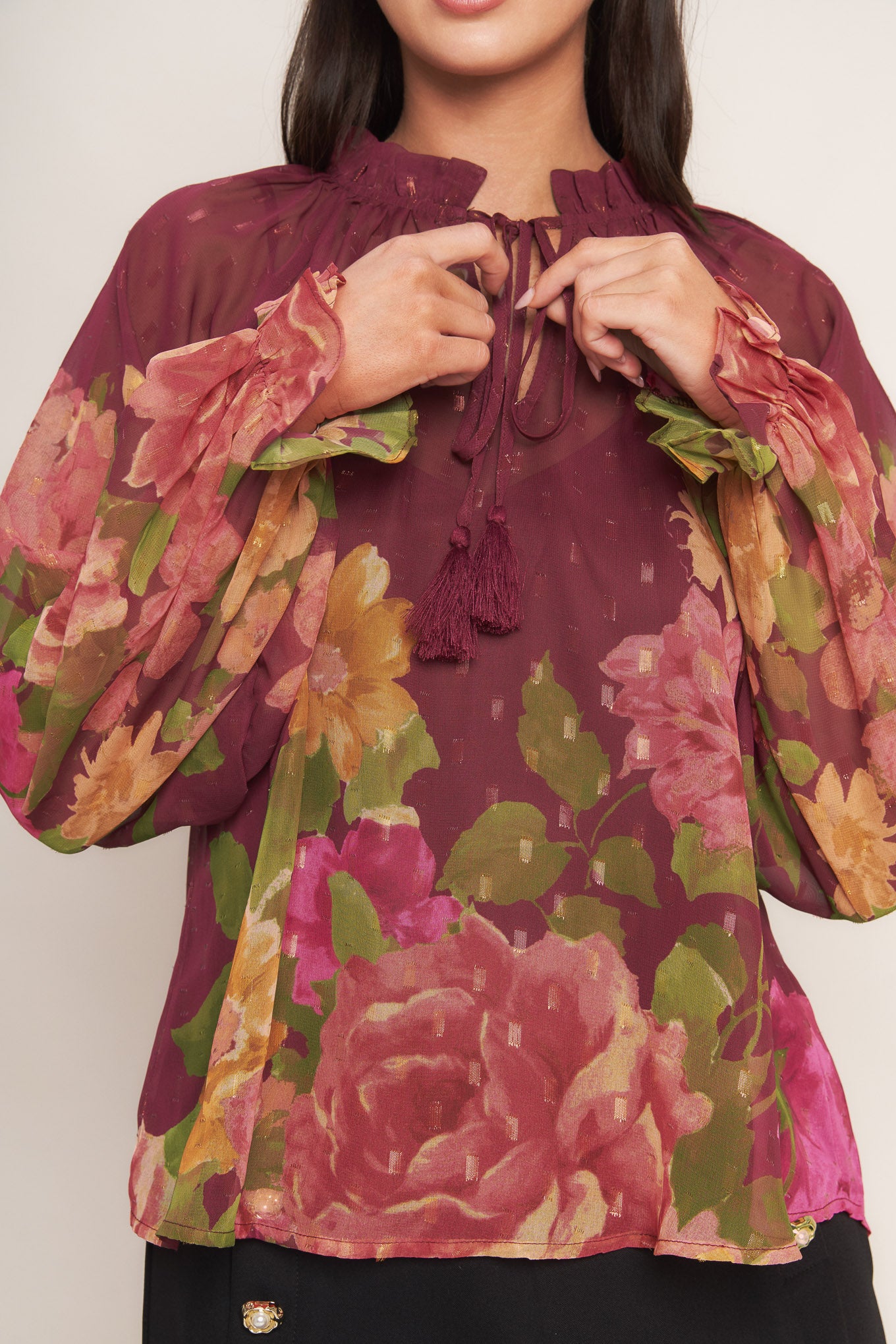 A printed textured woven top featuring ruffled round neckline with front tie, long sleeve with ruffled cuff and cami