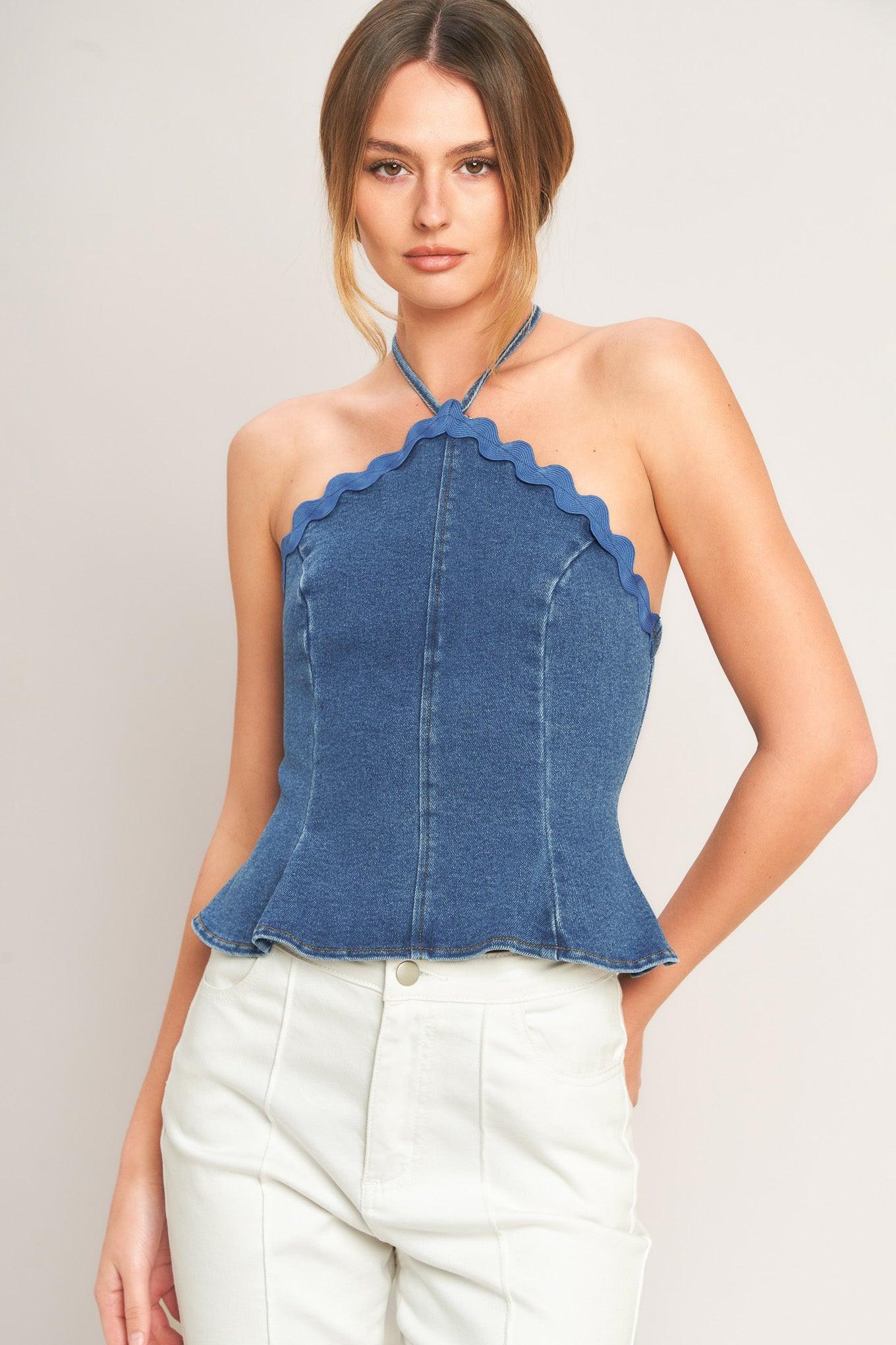 Woman wearing a blue denim halter top against a plain background