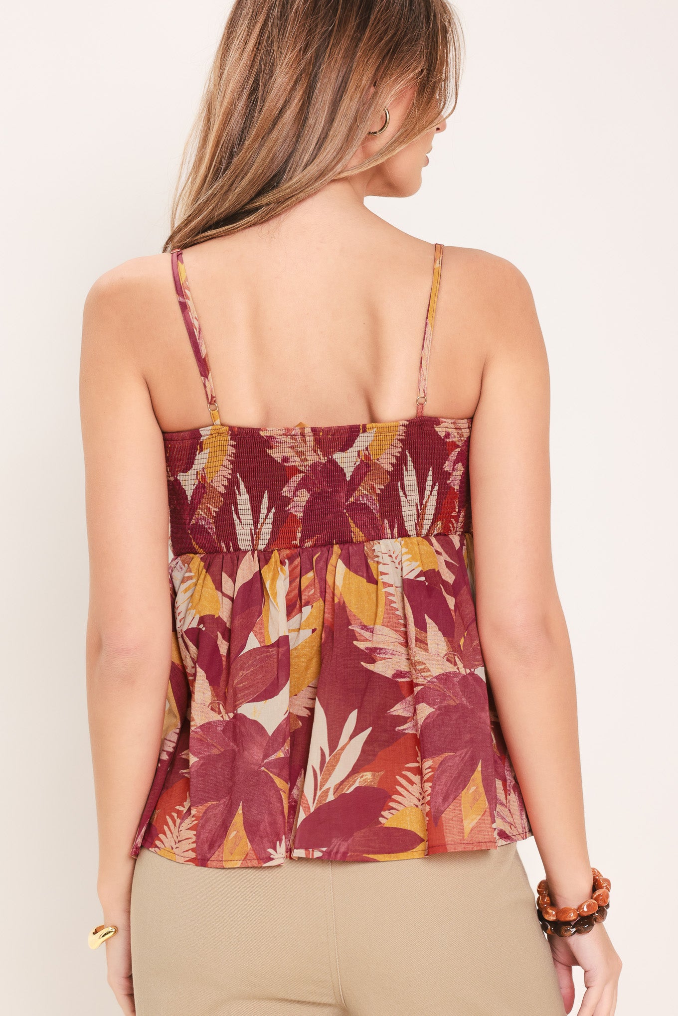 Woman wearing a burgundy printed woven top featuring cinched center, split front and smocked back bodice | Flying Tomato