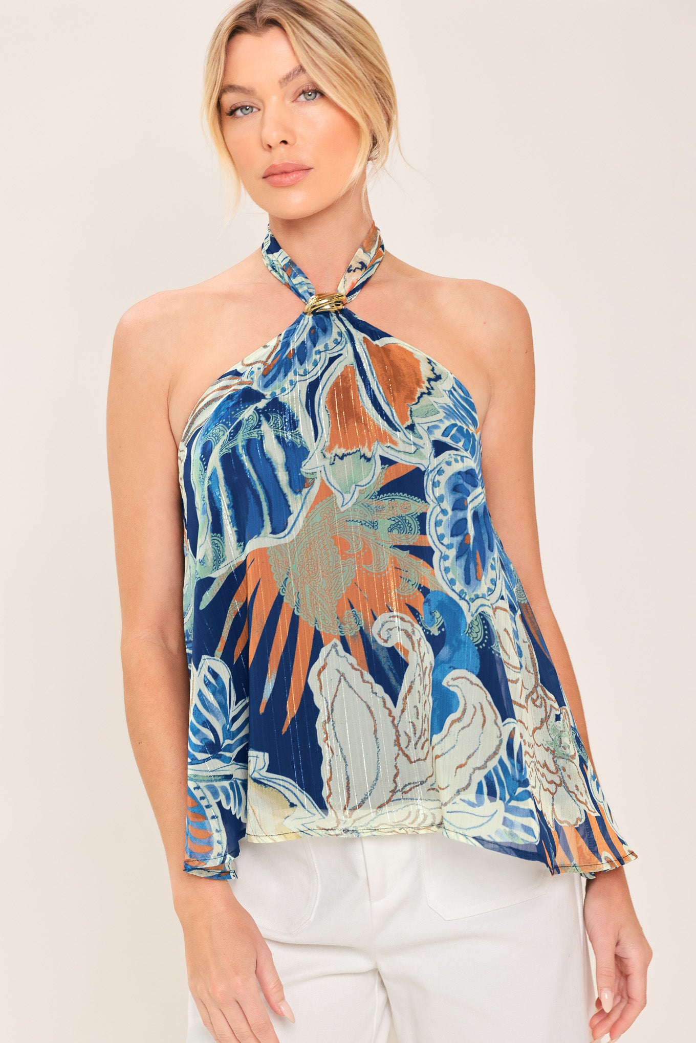 A woman wearing a halter-neck top with a tropical print in shades of blue, orange, and beige | Flying Tomato