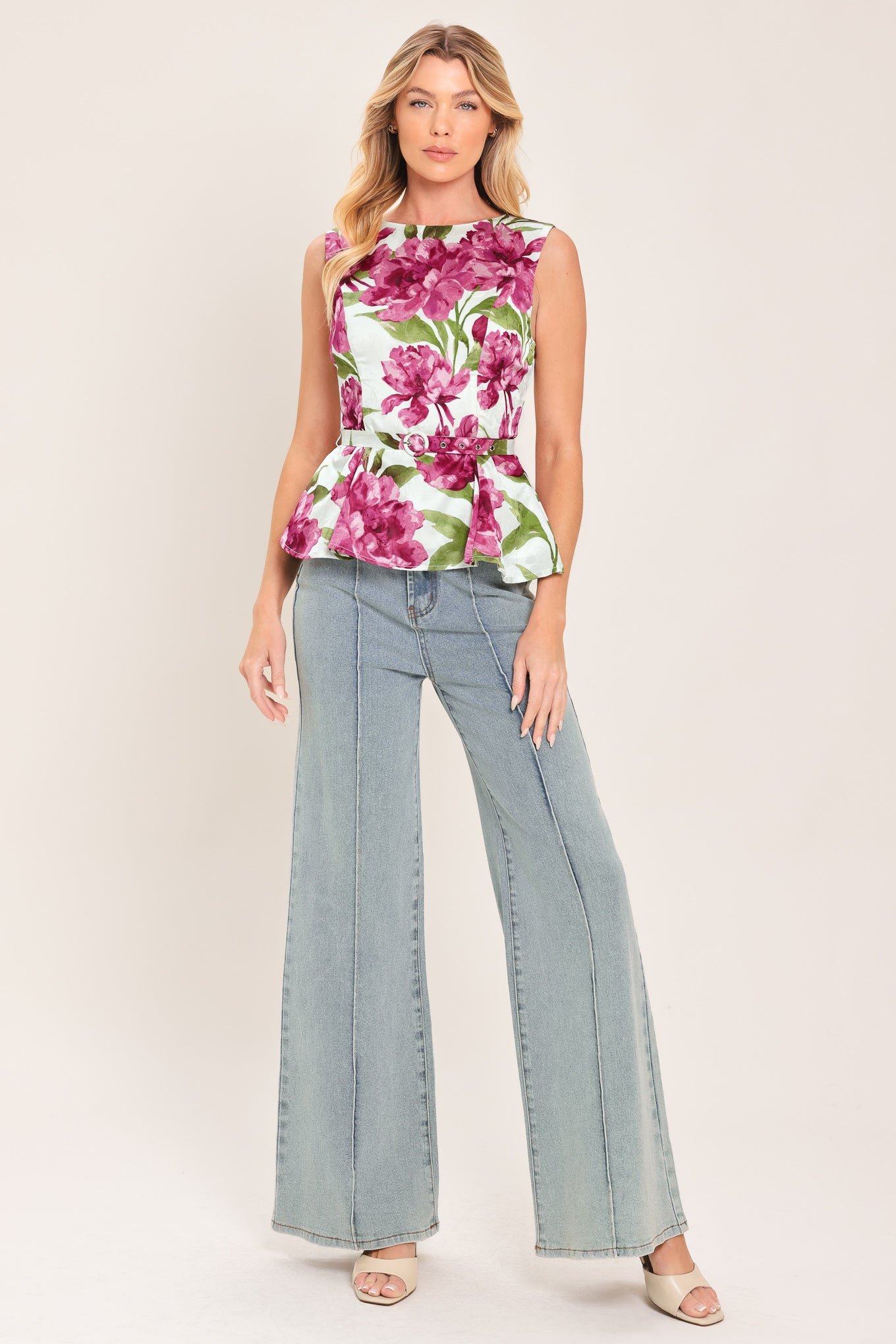 A woman wearing a sleeveless white peplum top with a vibrant pink and green floral print | Flying Tomato