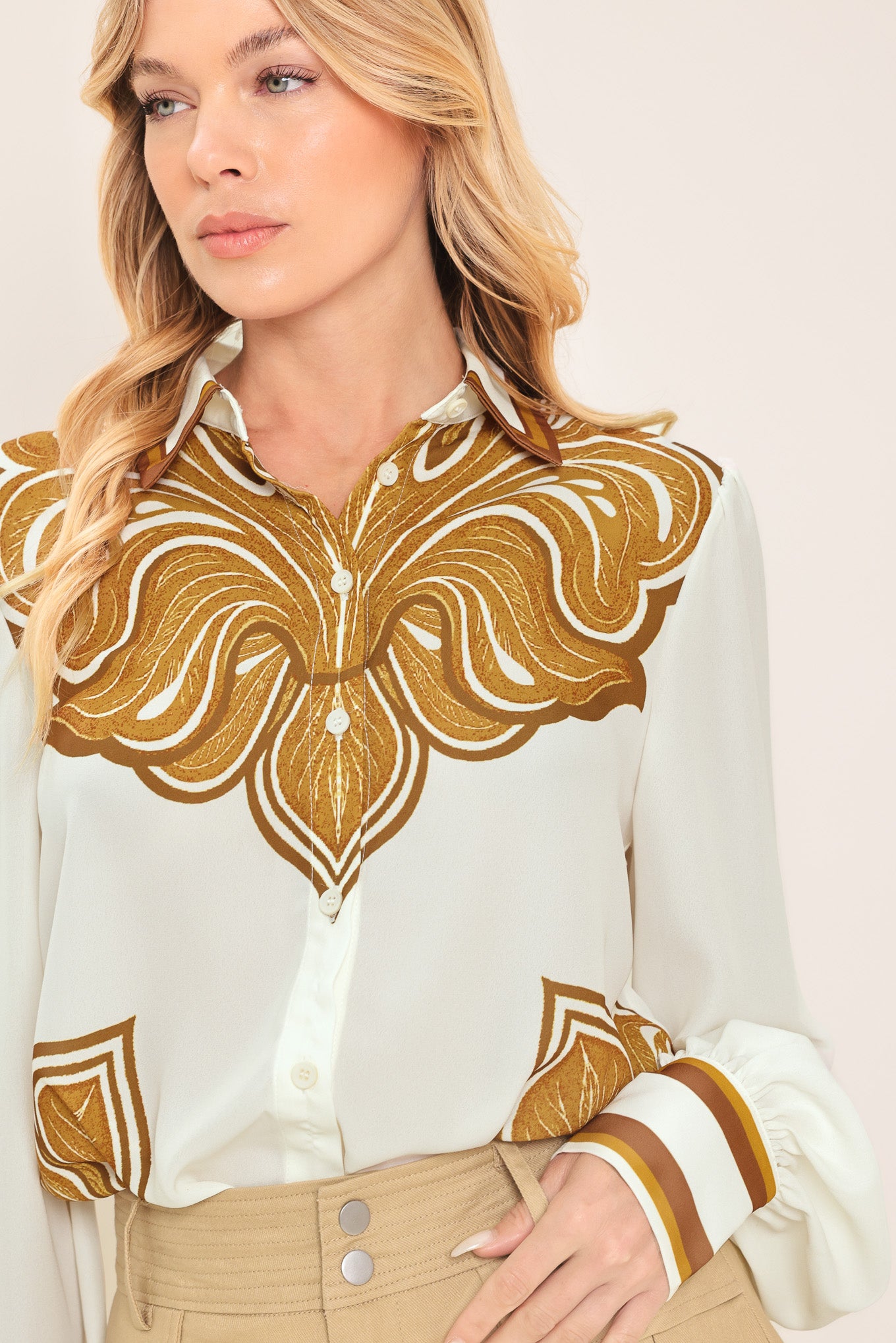 Woman wearing a white long sleeve button down blouse with brown leaf-like print | Flying Tomato
