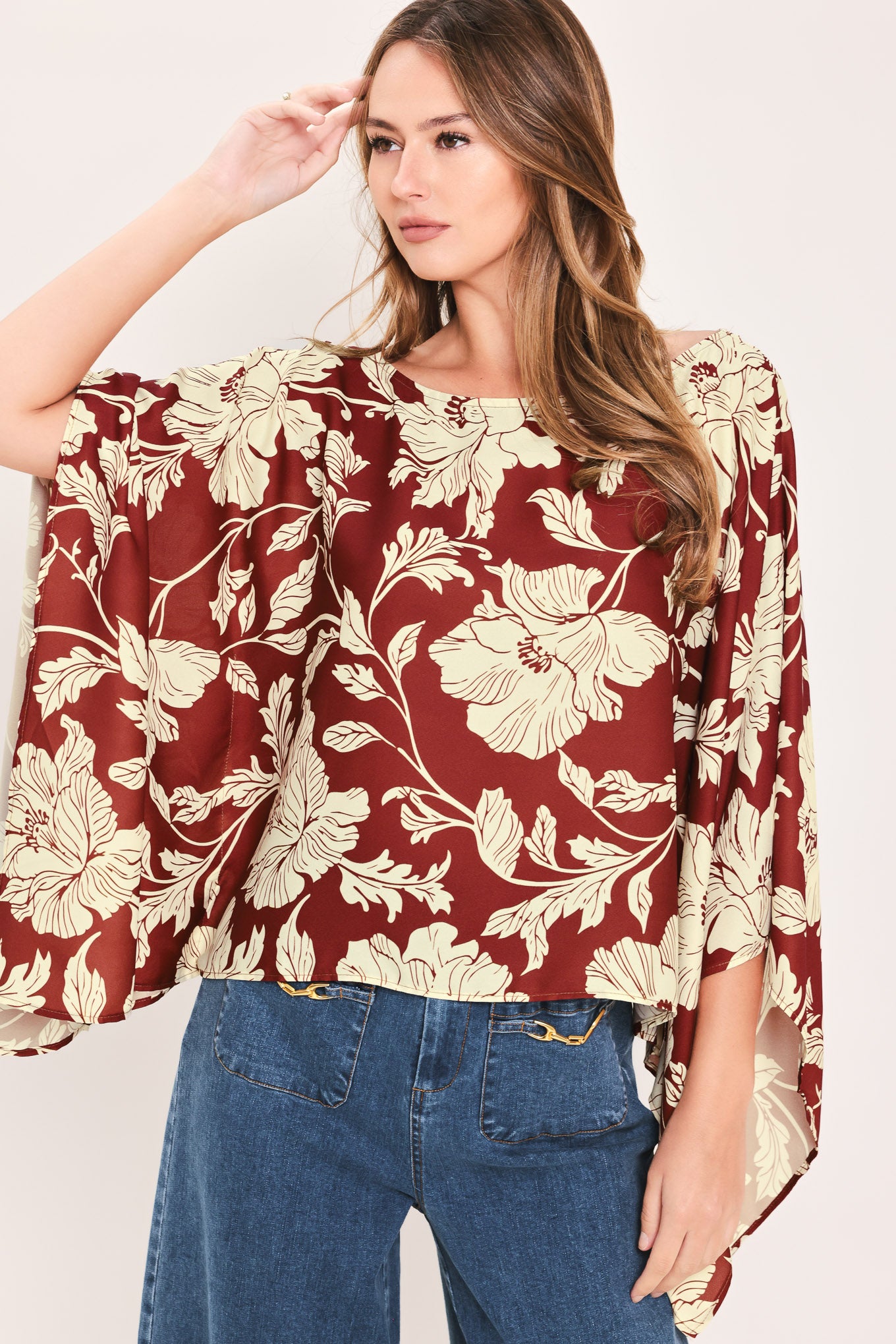 A woman wearing a burgundy and cream floral print top with wide bell sleeves | Flying Tomato