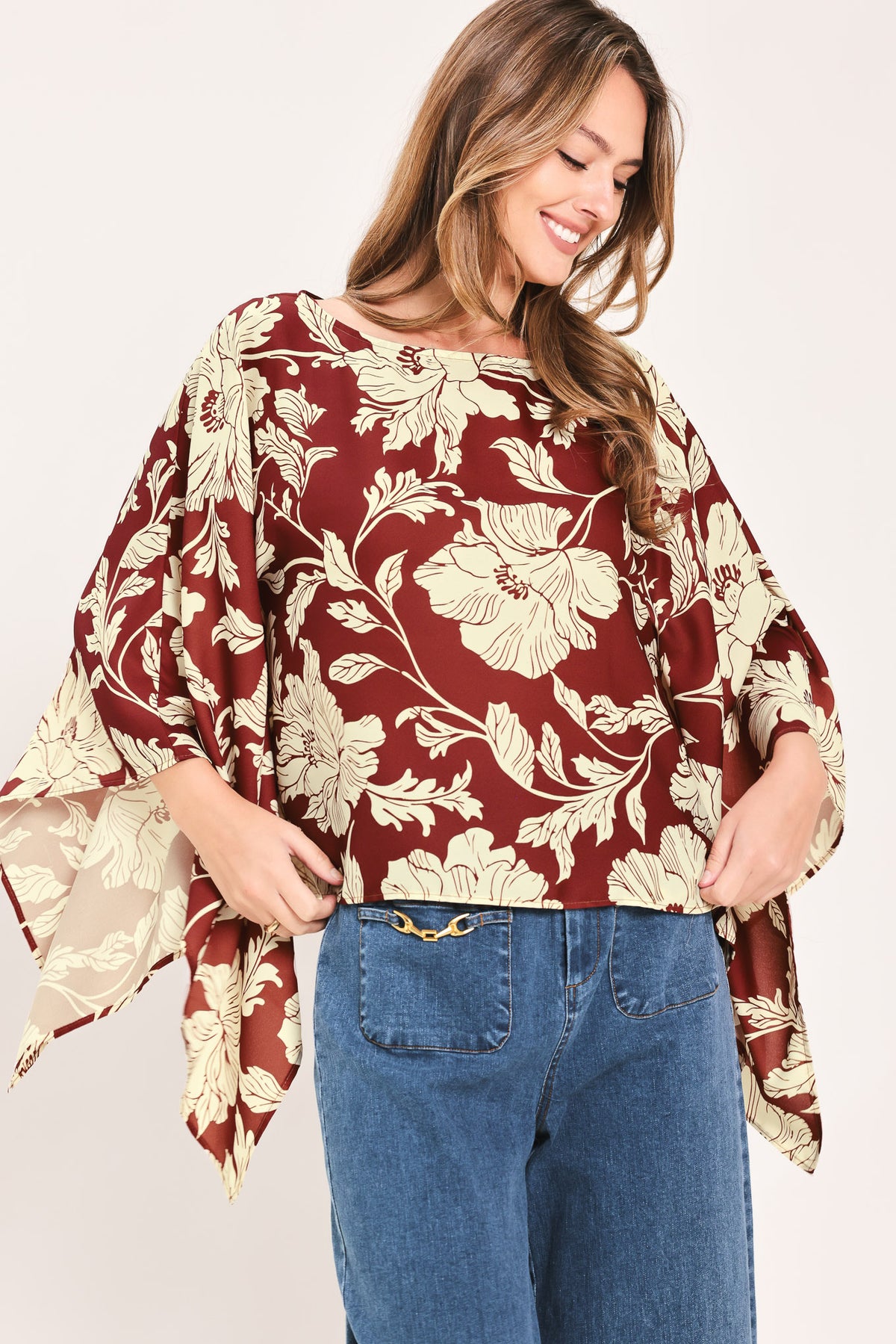 A woman wearing a burgundy and cream floral print top with wide bell sleeves | Flying Tomato
