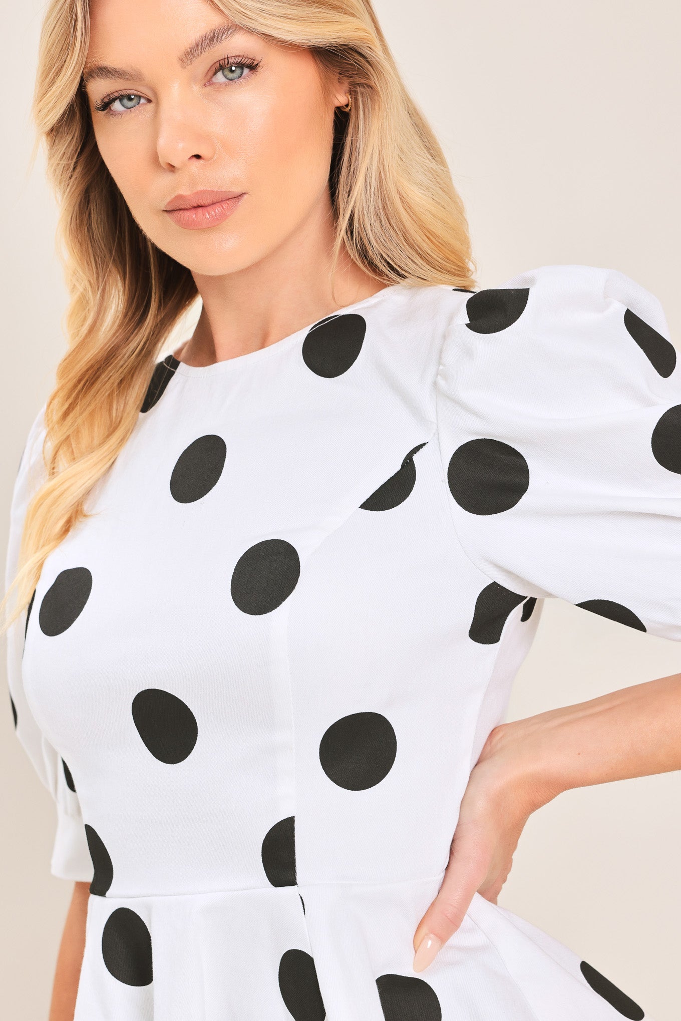 A woman wearing a white short-sleeve blouse with large black polka dots and puffed sleeves | Flying Tomato