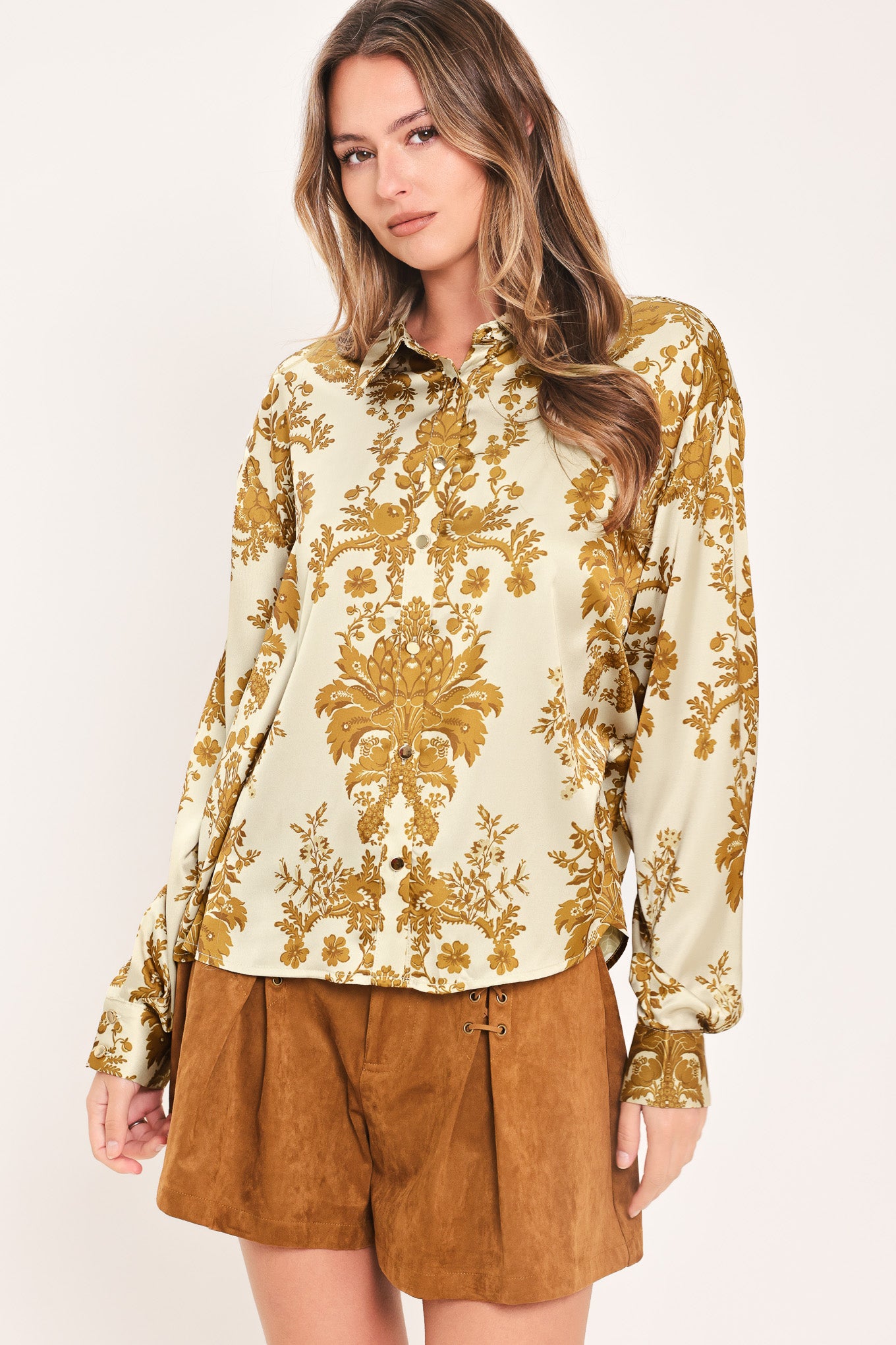 A woman wearing a long-sleeve button-up blouse with a beige and gold damask pattern | Flying Tomato