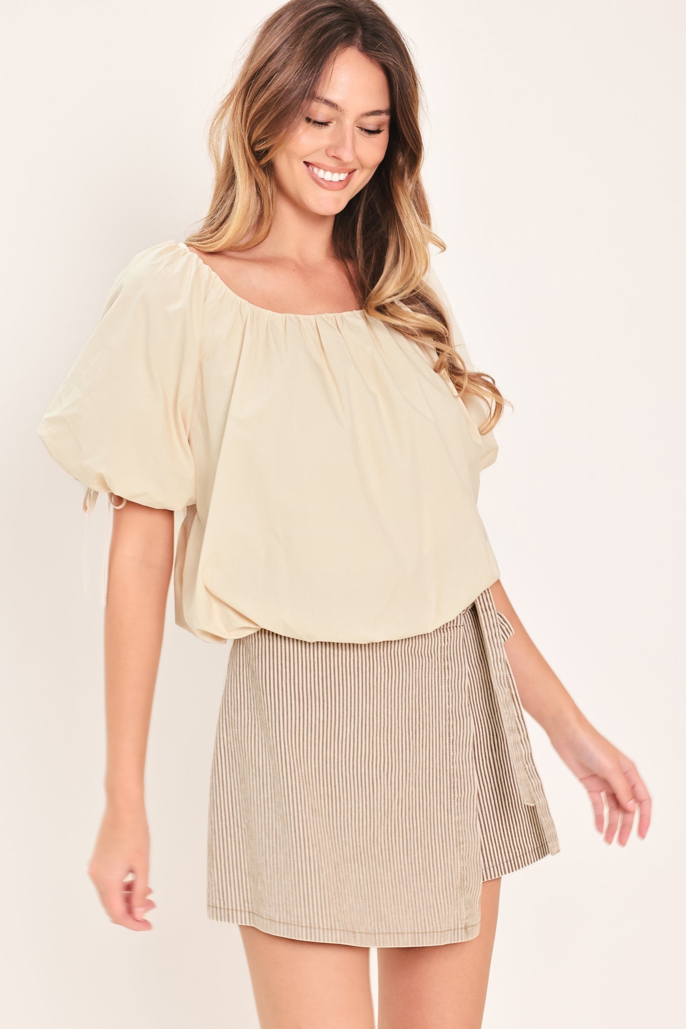 Woman wearing a light-beige stone top featuring wide neckline, short puff sleeve with tie and balloon waist | Flying Tomato