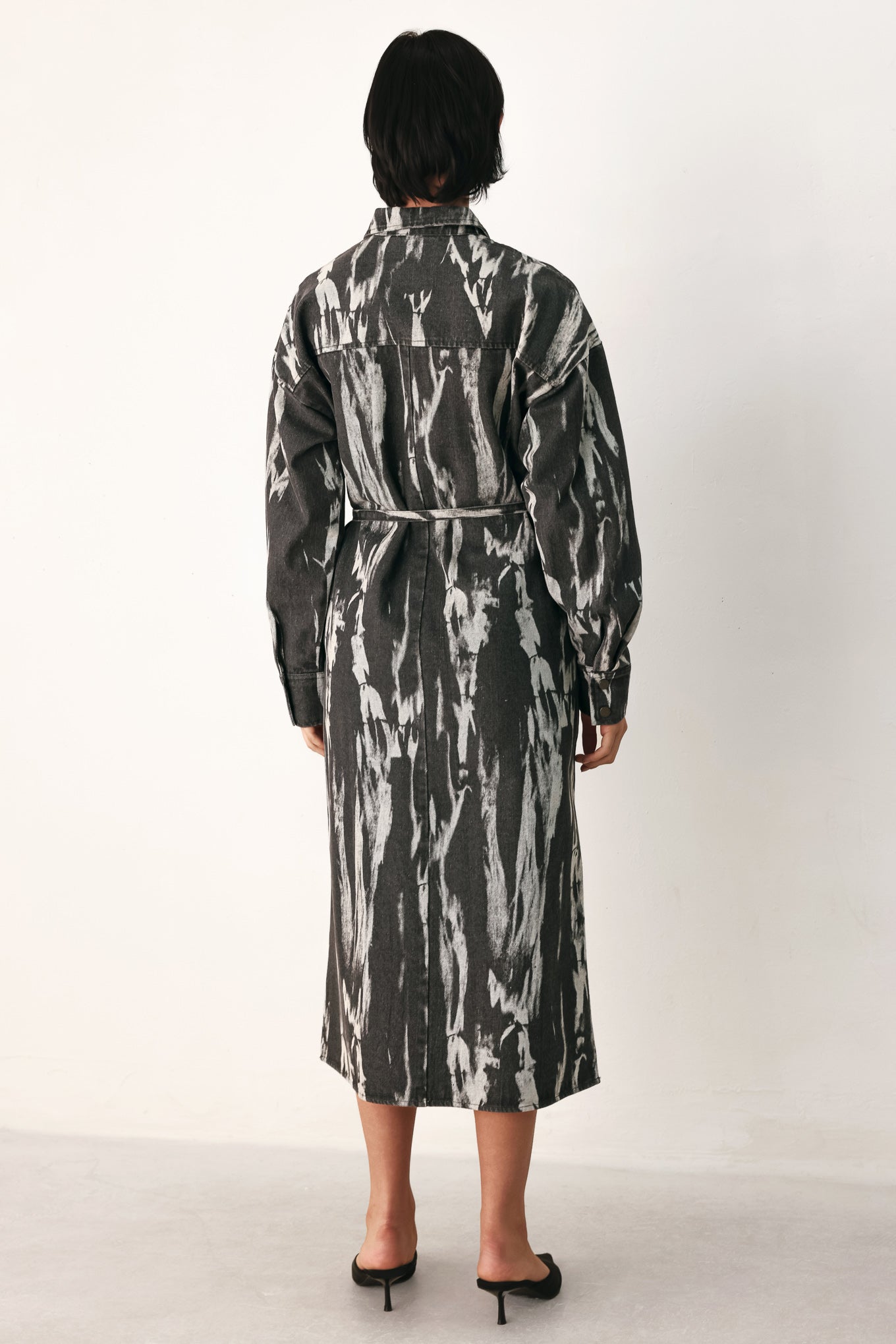 A woman modeling a long-sleeve button-front shirt denim midi dress with a gray and white abstract print | FREEMARKET