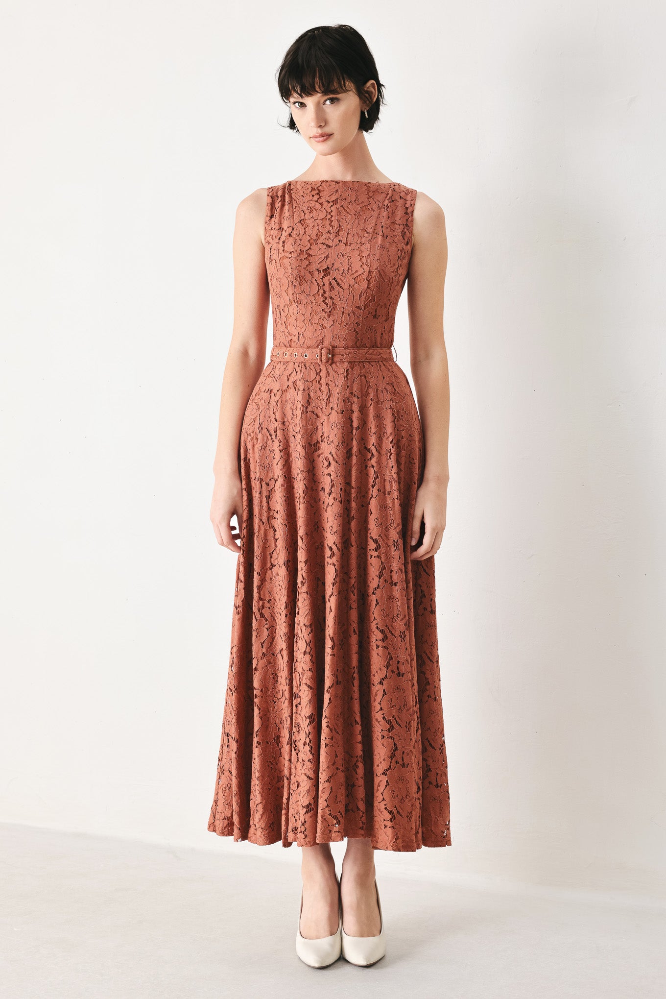 Woman wearing a rust colored lace midi dress featuring wide neckline, sleeveless, self belt, full circle skirt and back zipper closure | FREEMARKET