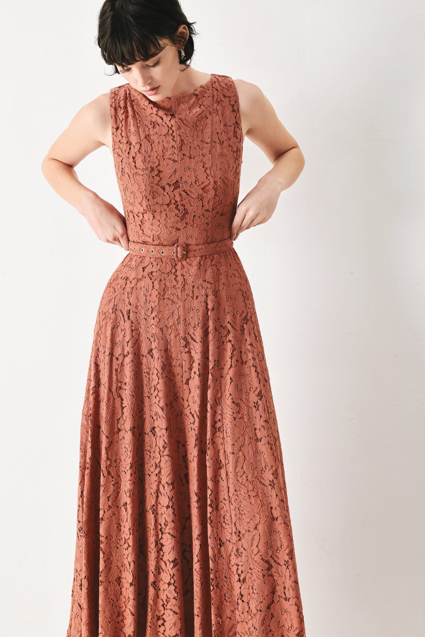 Woman wearing a rust colored lace midi dress featuring wide neckline, sleeveless, self belt, full circle skirt and back zipper closure | FREEMARKET