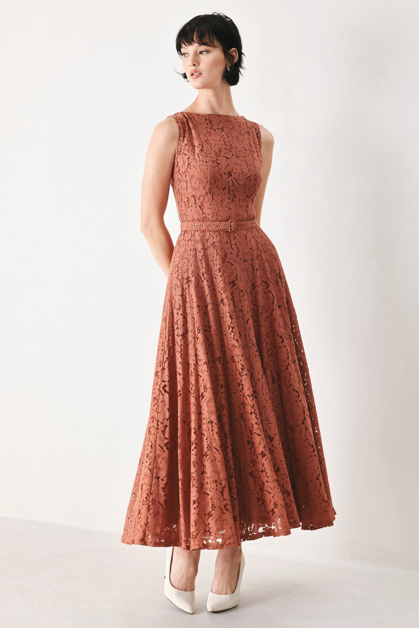 Woman wearing a rust colored lace midi dress featuring wide neckline, sleeveless, self belt, full circle skirt and back zipper closure | FREEMARKET