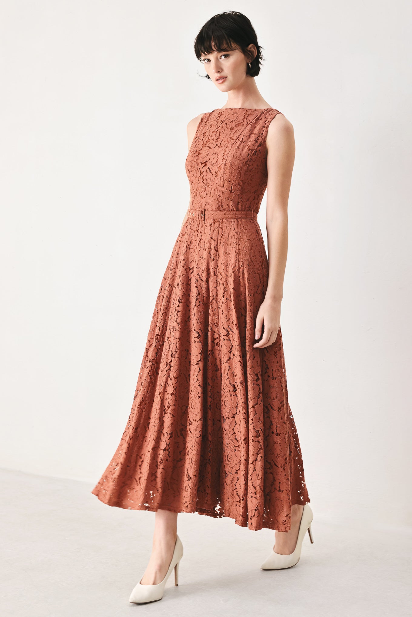 Woman wearing a rust colored lace midi dress featuring wide neckline, sleeveless, self belt, full circle skirt and back zipper closure | FREEMARKET
