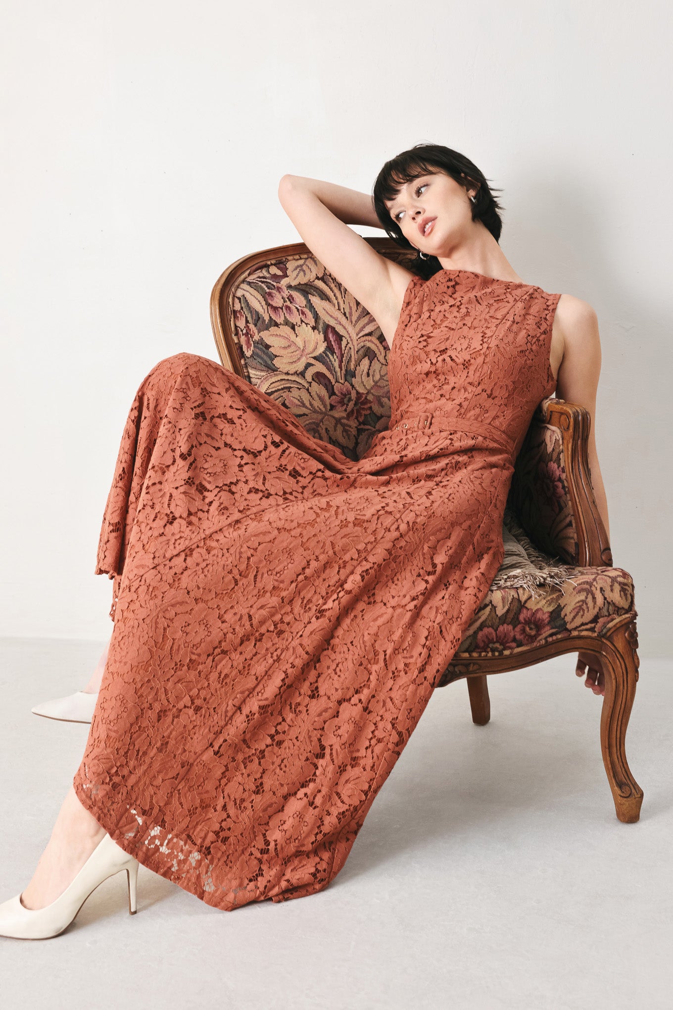 Woman wearing a rust colored lace midi dress featuring wide neckline, sleeveless, self belt, full circle skirt and back zipper closure | FREEMARKET