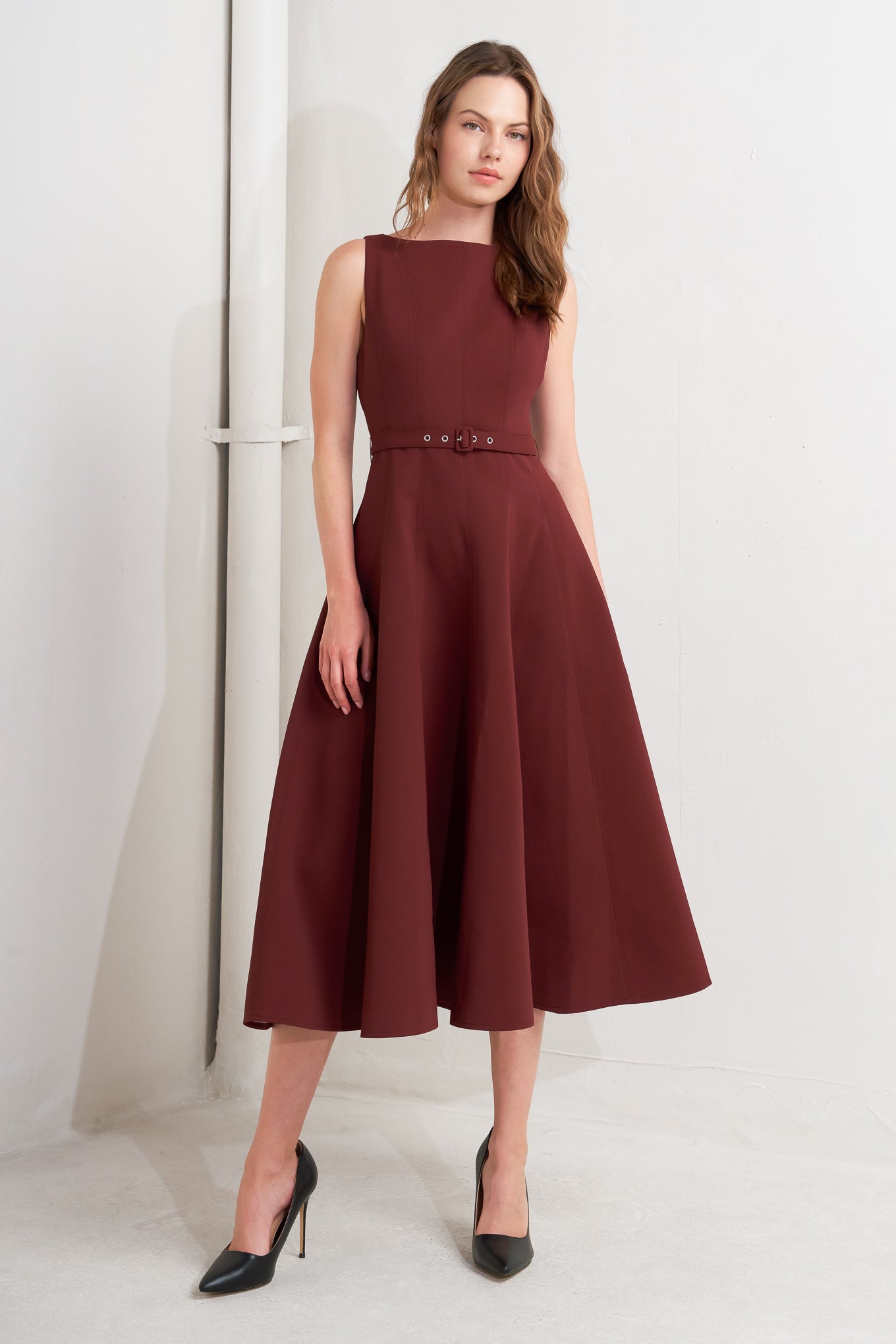 A solid woven midi dress featuring boat neckline, sleeveless, full skirt, self belt, side pocket and full skirt