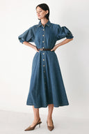 Woman wearing a blue denim dress with a belt on a beige background