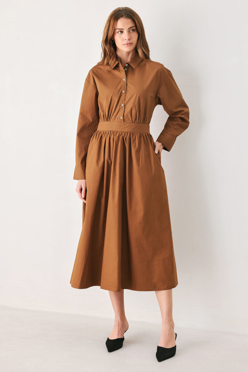 A woman modeling a rust long-sleeve midi shirt dress with a button-up front and gathered waist | FREEMARKET