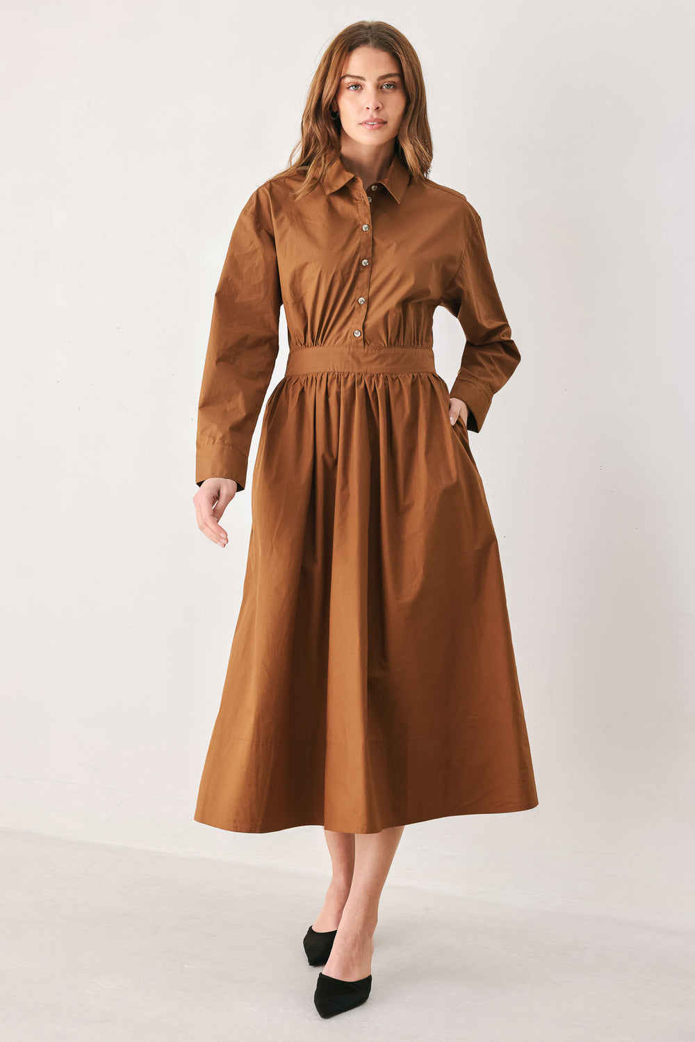 A woman modeling a rust long-sleeve midi shirt dress with a button-up front and gathered waist | FREEMARKET