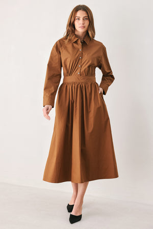 A woman modeling a rust long-sleeve midi shirt dress with a button-up front and gathered waist | FREEMARKET