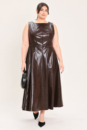A woman modeling a sleeveless, dark brown faux-leather midi dress with a matching waist belt, paired with black pointed-toe heels and a small black handbag, against a plain light background | FREEMARKET Curve