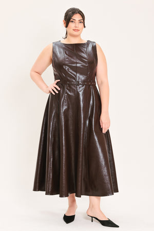 A woman modeling a sleeveless, dark brown faux-leather midi dress with a matching waist belt, paired with black pointed-toe heels and a small black handbag, against a plain light background | FREEMARKET Curve