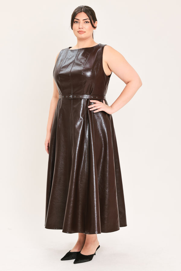 A woman modeling a sleeveless, dark brown faux-leather midi dress with a matching waist belt, paired with black pointed-toe heels and a small black handbag, against a plain light background | FREEMARKET Curve