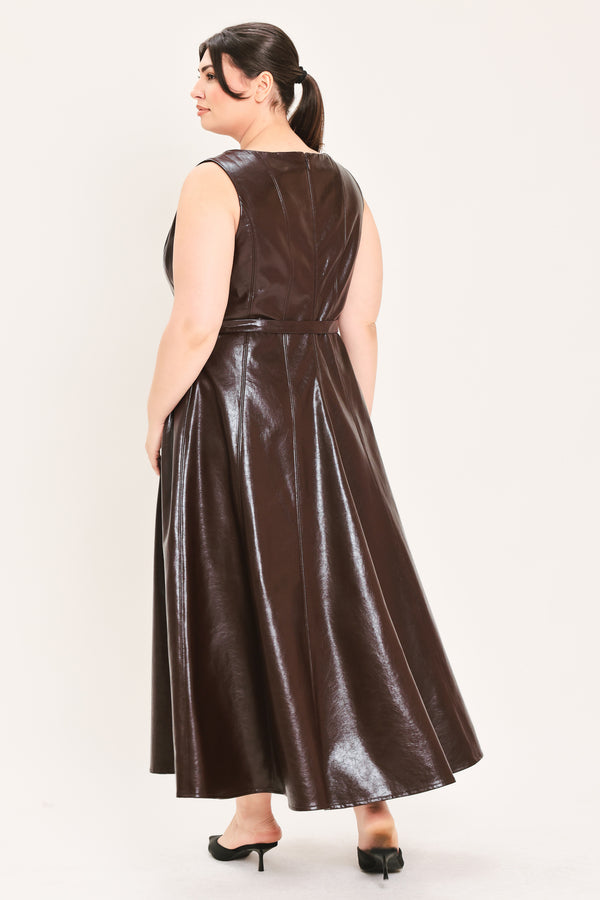 A woman modeling a sleeveless, dark brown faux-leather midi dress with a matching waist belt, paired with black pointed-toe heels and a small black handbag, against a plain light background | FREEMARKET Curve