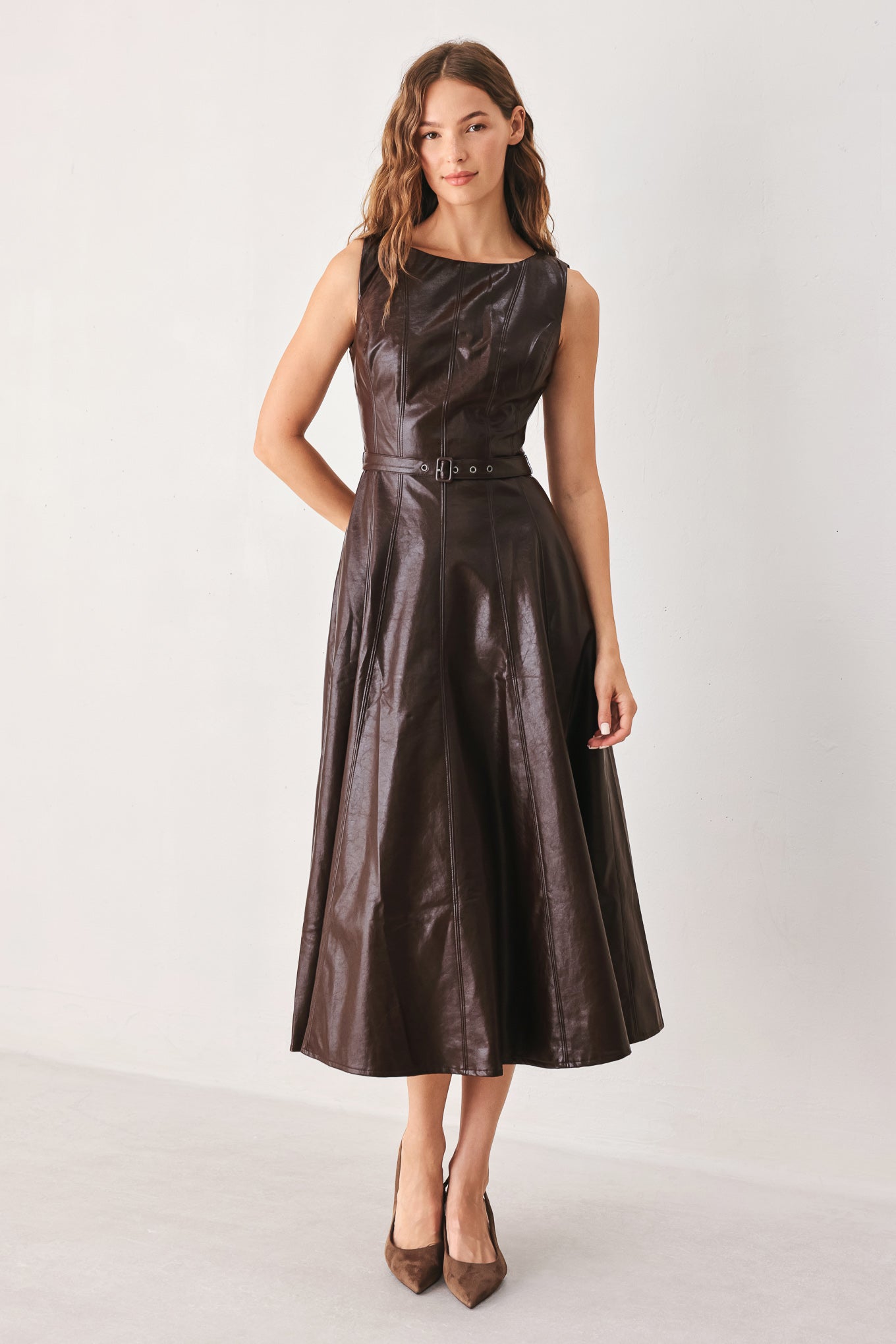 A woman wearing a sleeveless, dark brown faux-leather midi dress with a defined waist belt and a flared skirt | FREEMARKET