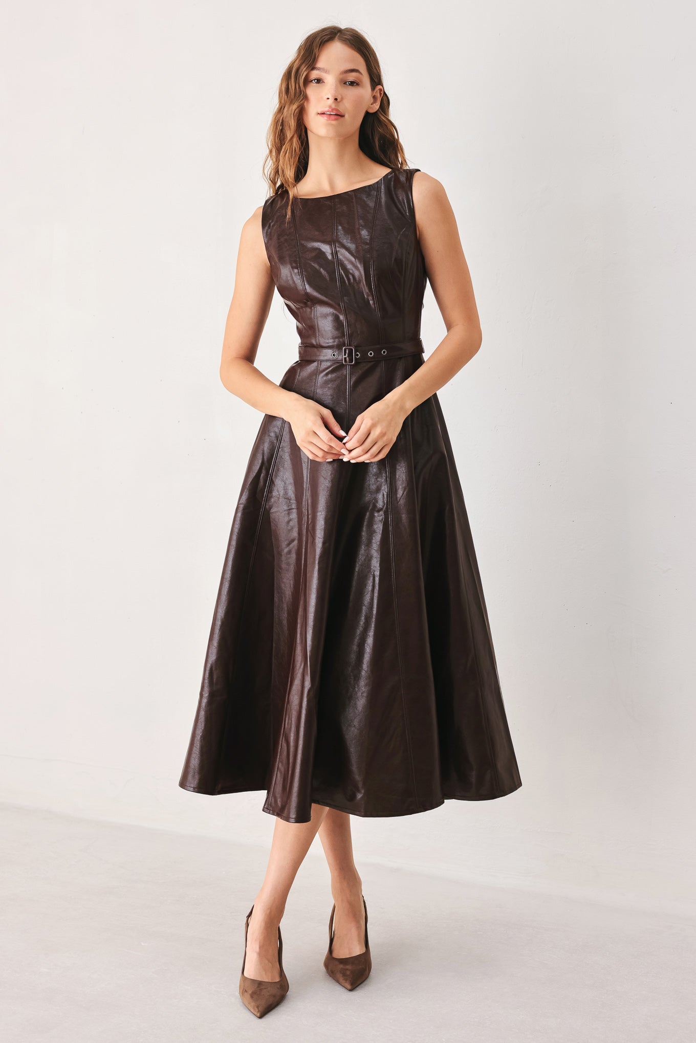 A woman wearing a sleeveless, dark brown faux-leather midi dress with a defined waist belt and a flared skirt | FREEMARKET