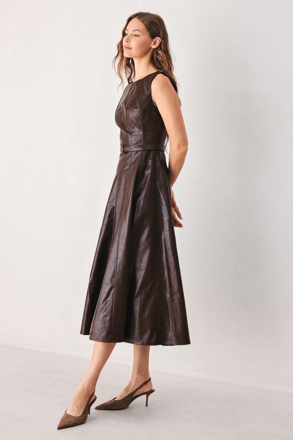 A woman wearing a sleeveless, dark brown faux-leather midi dress with a defined waist belt and a flared skirt | FREEMARKET